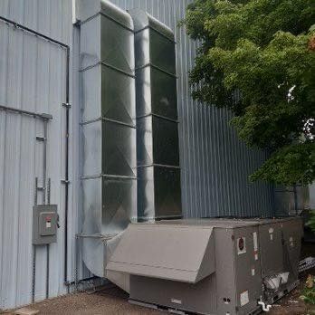 HVAC unit with ductwork installed on a building's exterior wall.