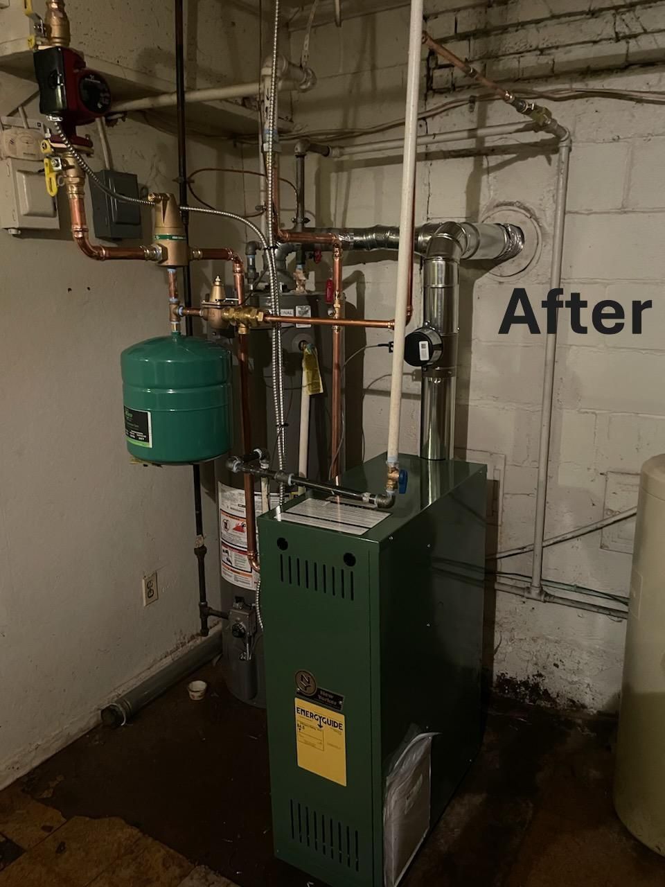 Green furnace and tank in basement with copper pipes. 