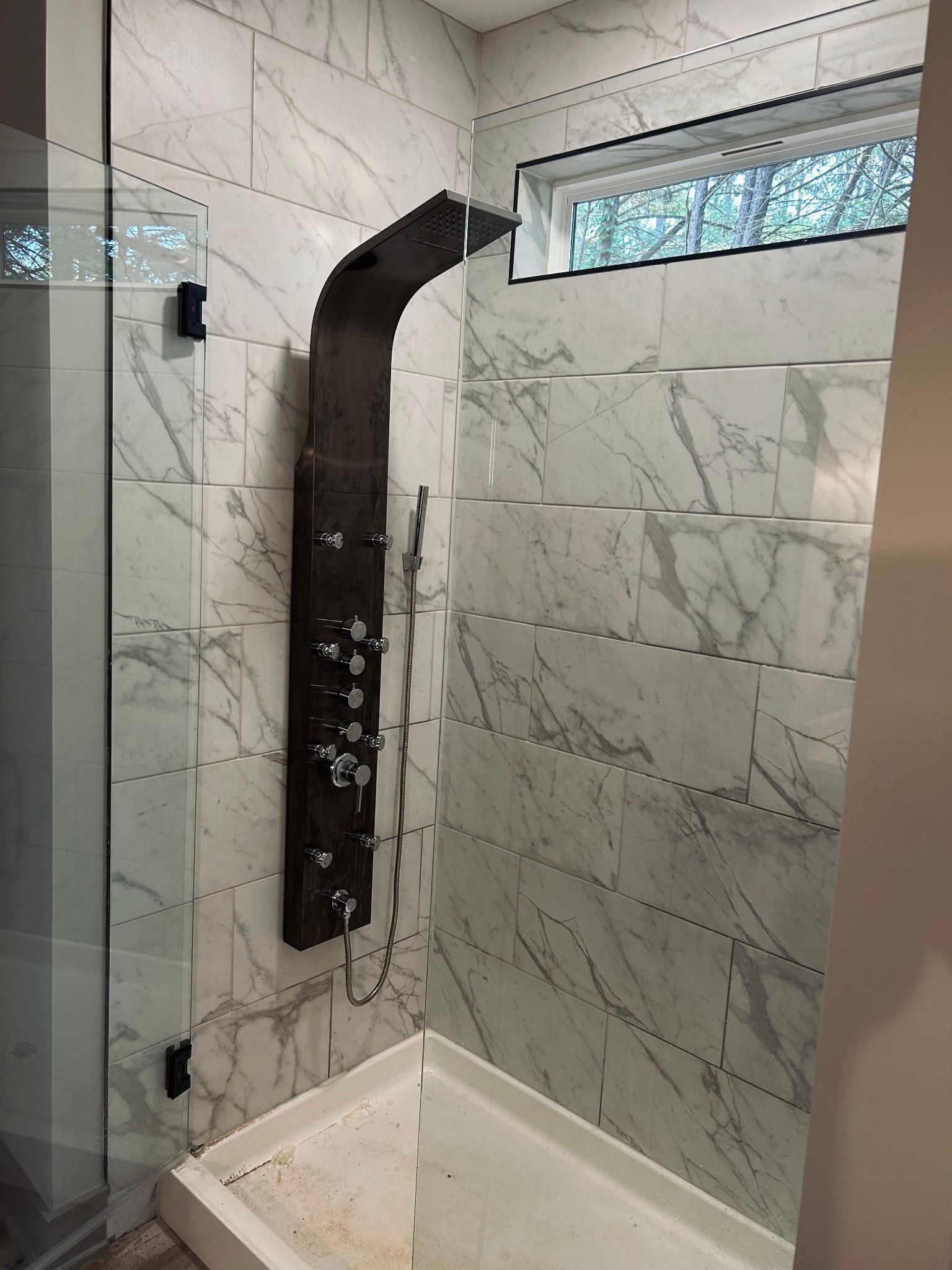 Gloved hands cutting a white PVC pipe with a red cutter outdoors on the ground.