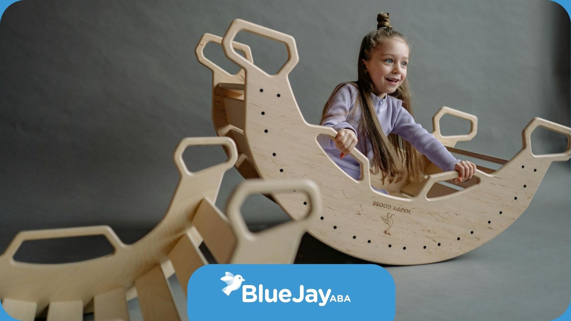 A girl with ADHD playing on a large wooden rocker in a playroom during ABA therapy session in NC.