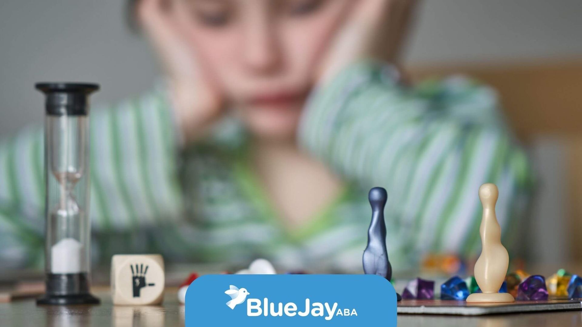 Autistic child with striped shirt showing frustration while playing a board game during ABA therapy.