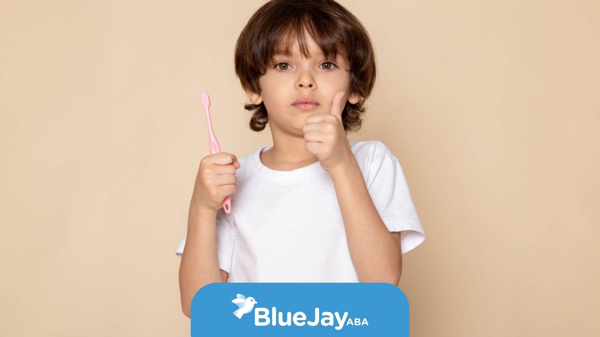 Young child with autism holding a toothbrush and giving a thumbs-up gesture.