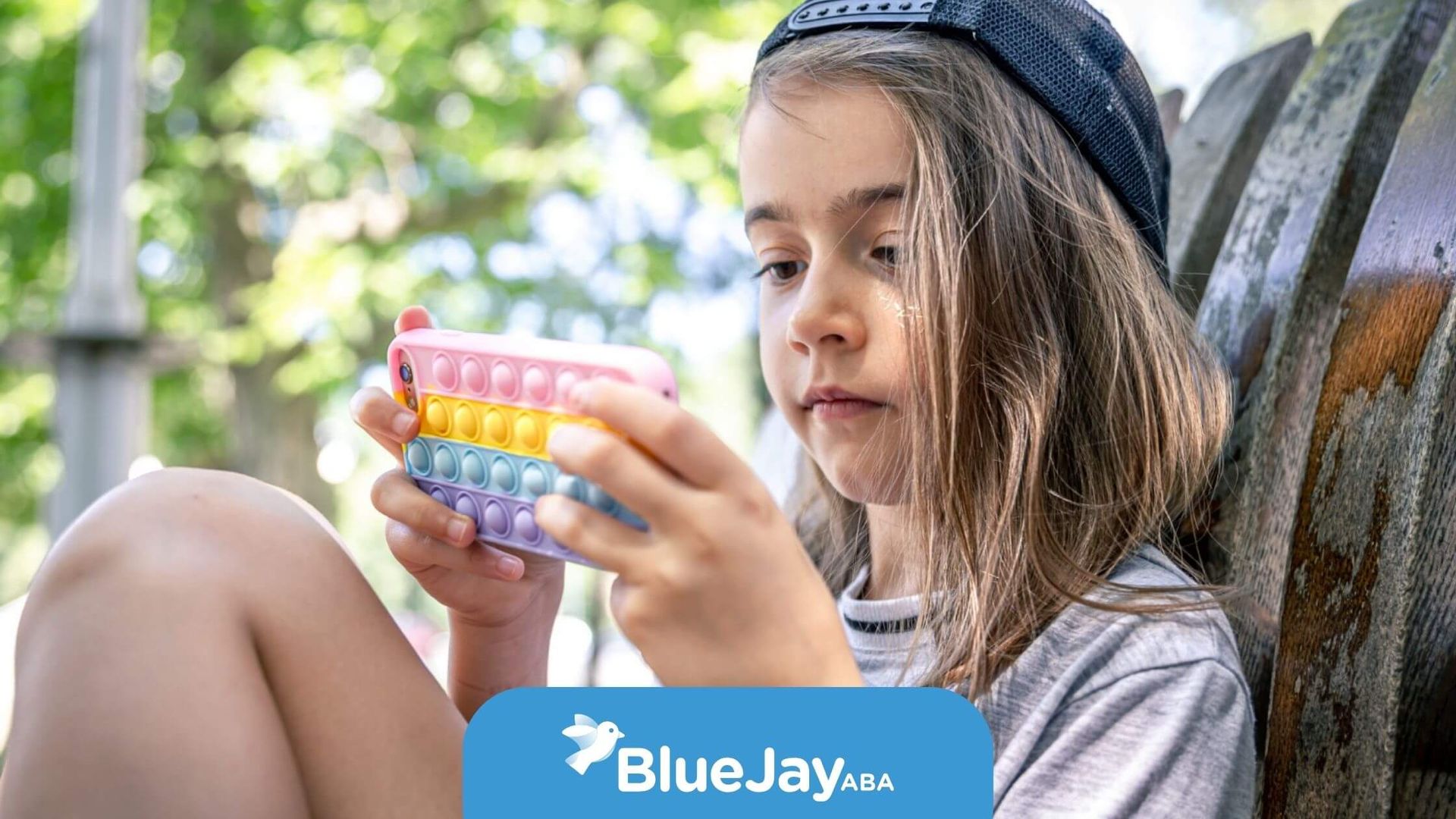 Girl with autism sitting outdoors using a fidget toy.