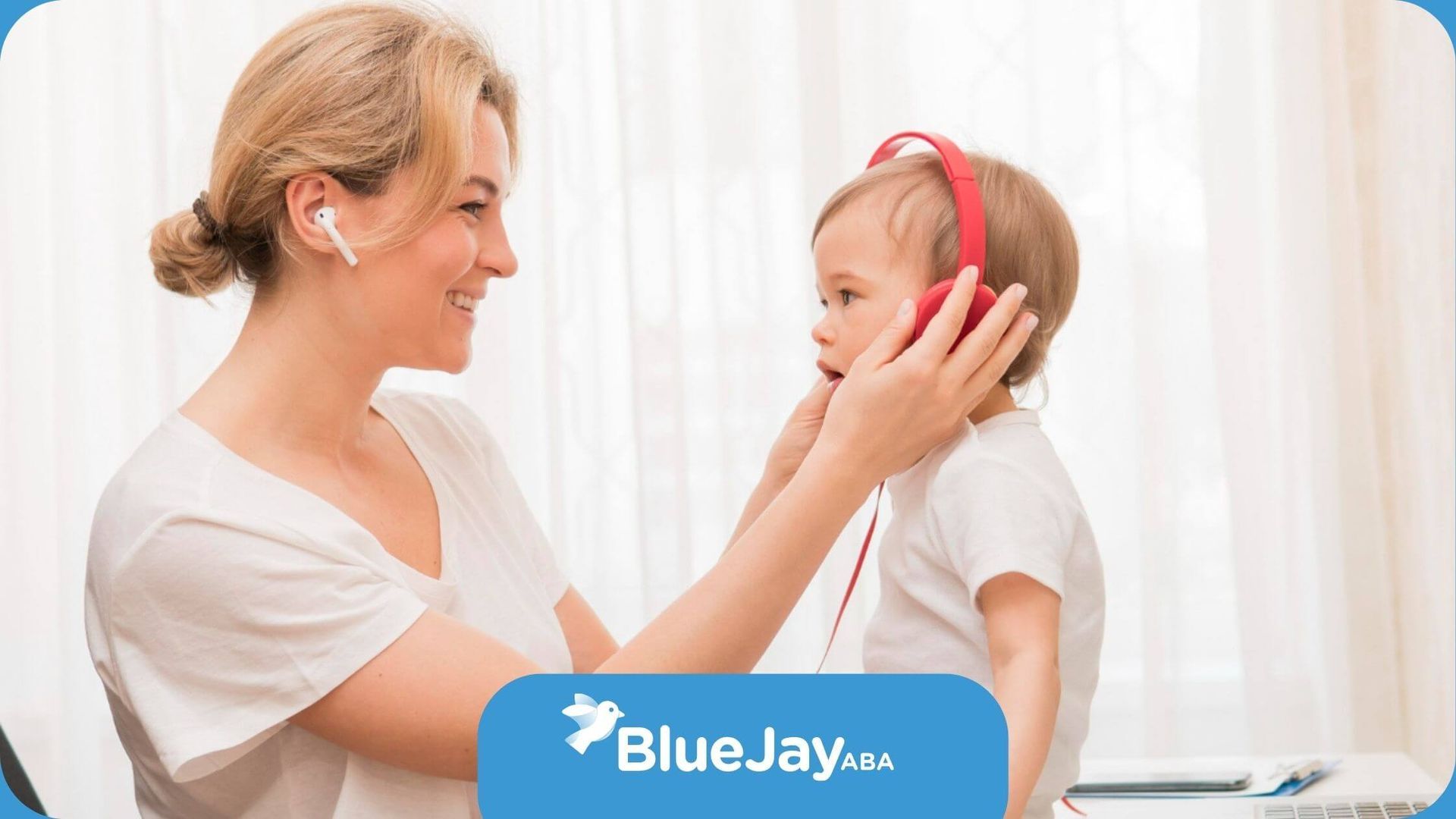 ABA therapist helping toddler with headphones during interactive learning session.
