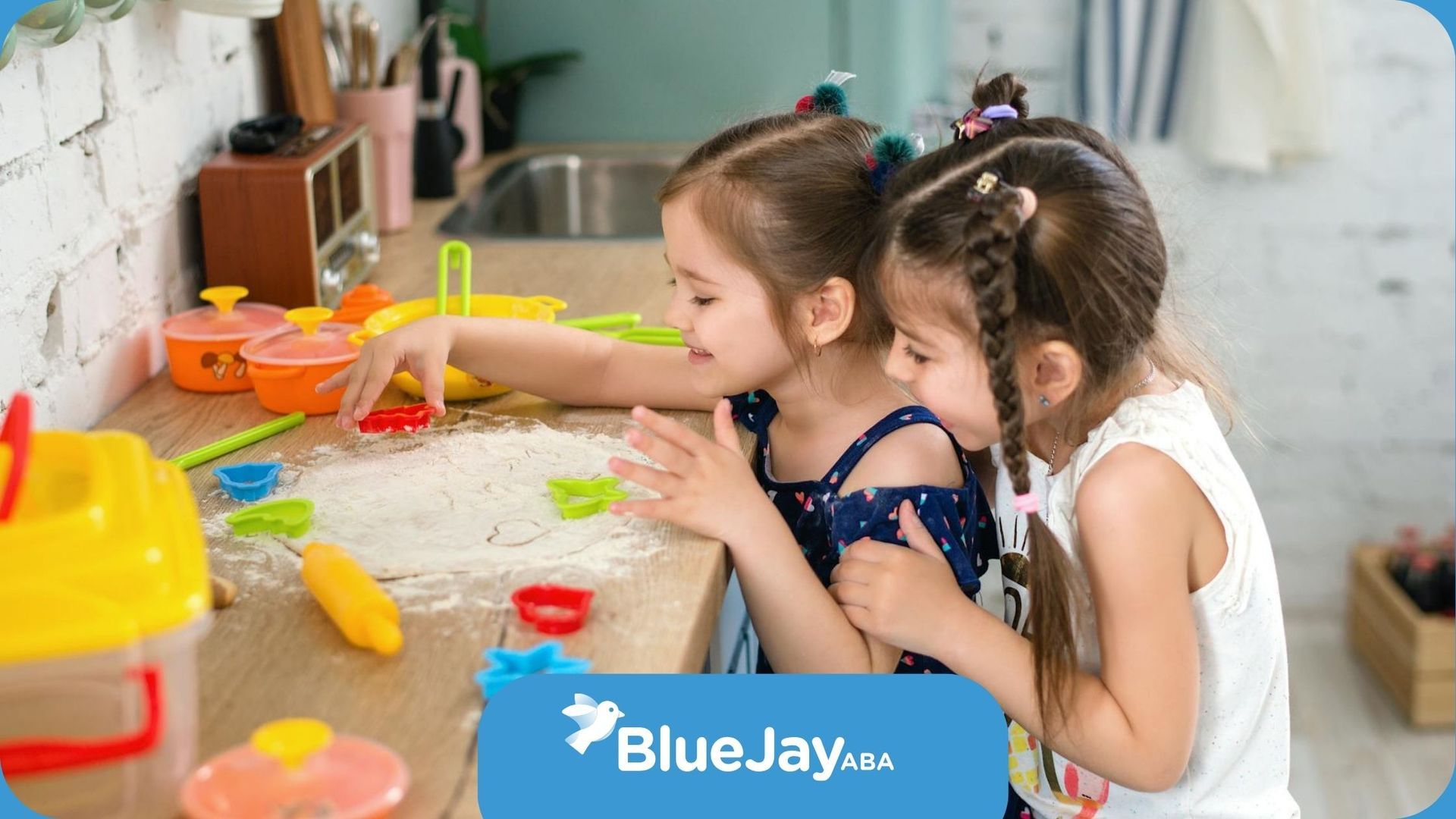 Autistic girls playing with dough and cookie cutters on a kitchen counter during ABA therapy in NC.