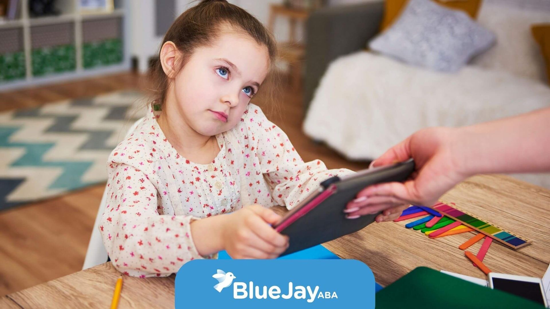 Autistic child with a bored expression after therapy while staring at a tablet during a task.