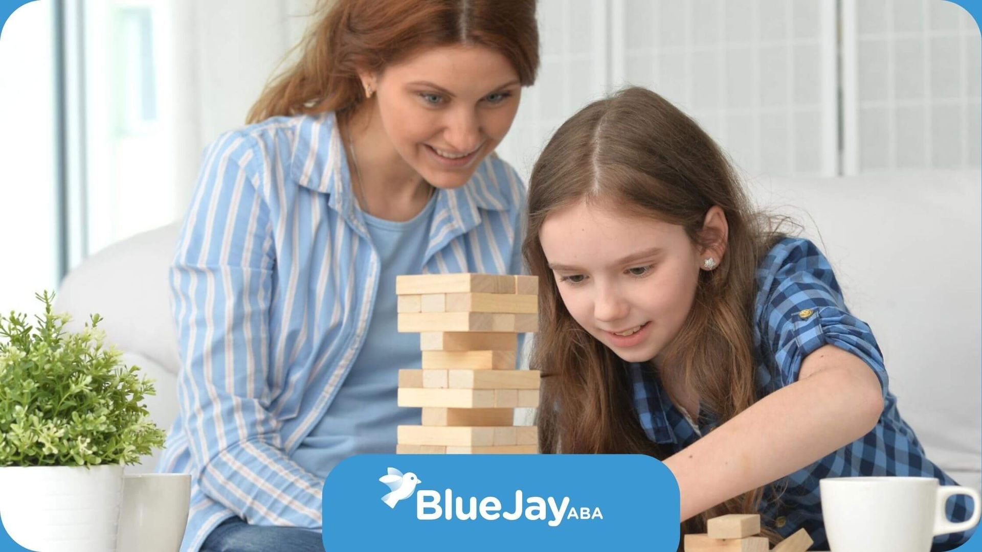 Therapist supporting young girl with autism in a Jenga block activity during ABA session.
