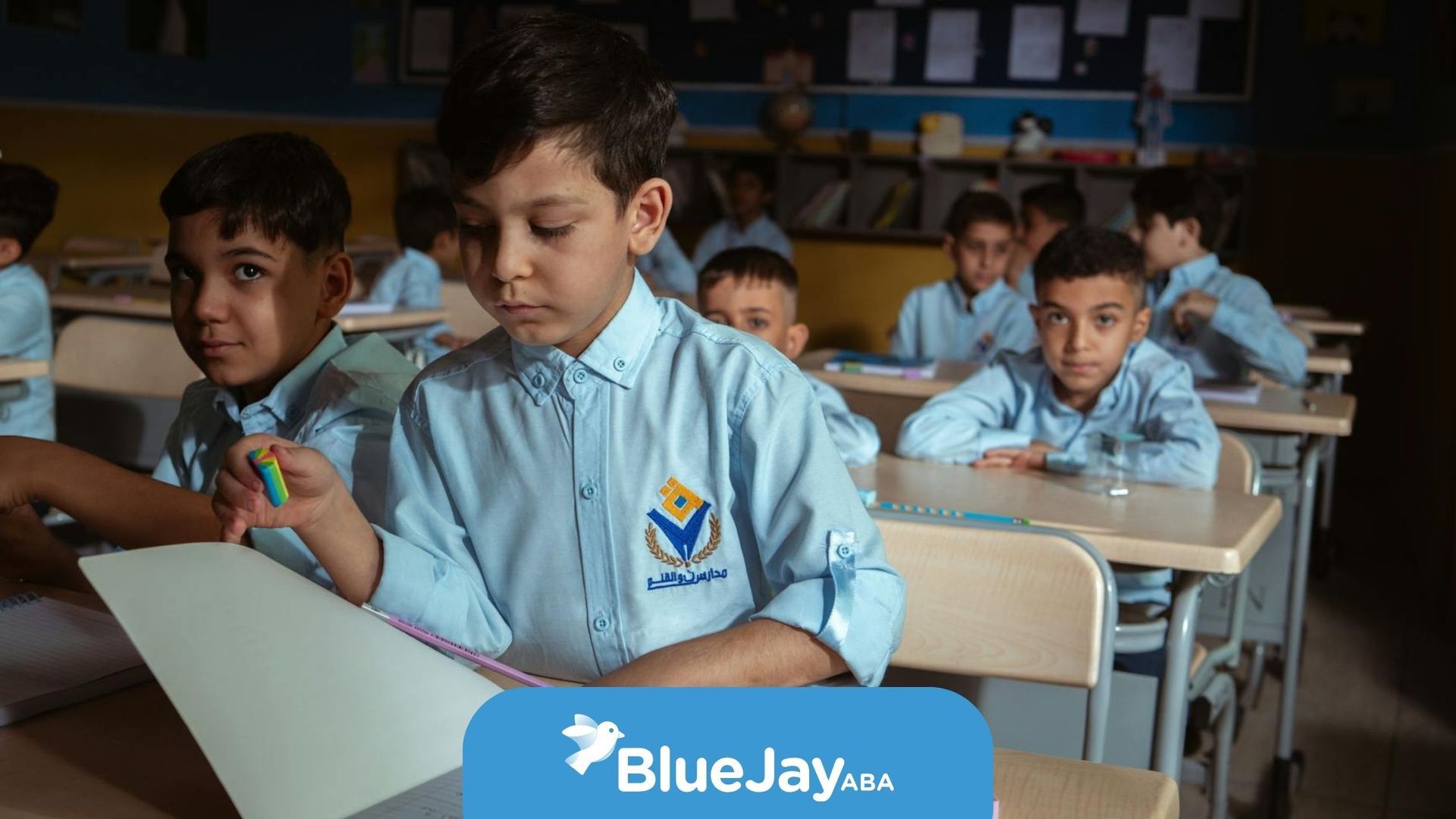 Boys in classroom wearing matching uniforms with autistic boy standing as he reads his paper in NC.