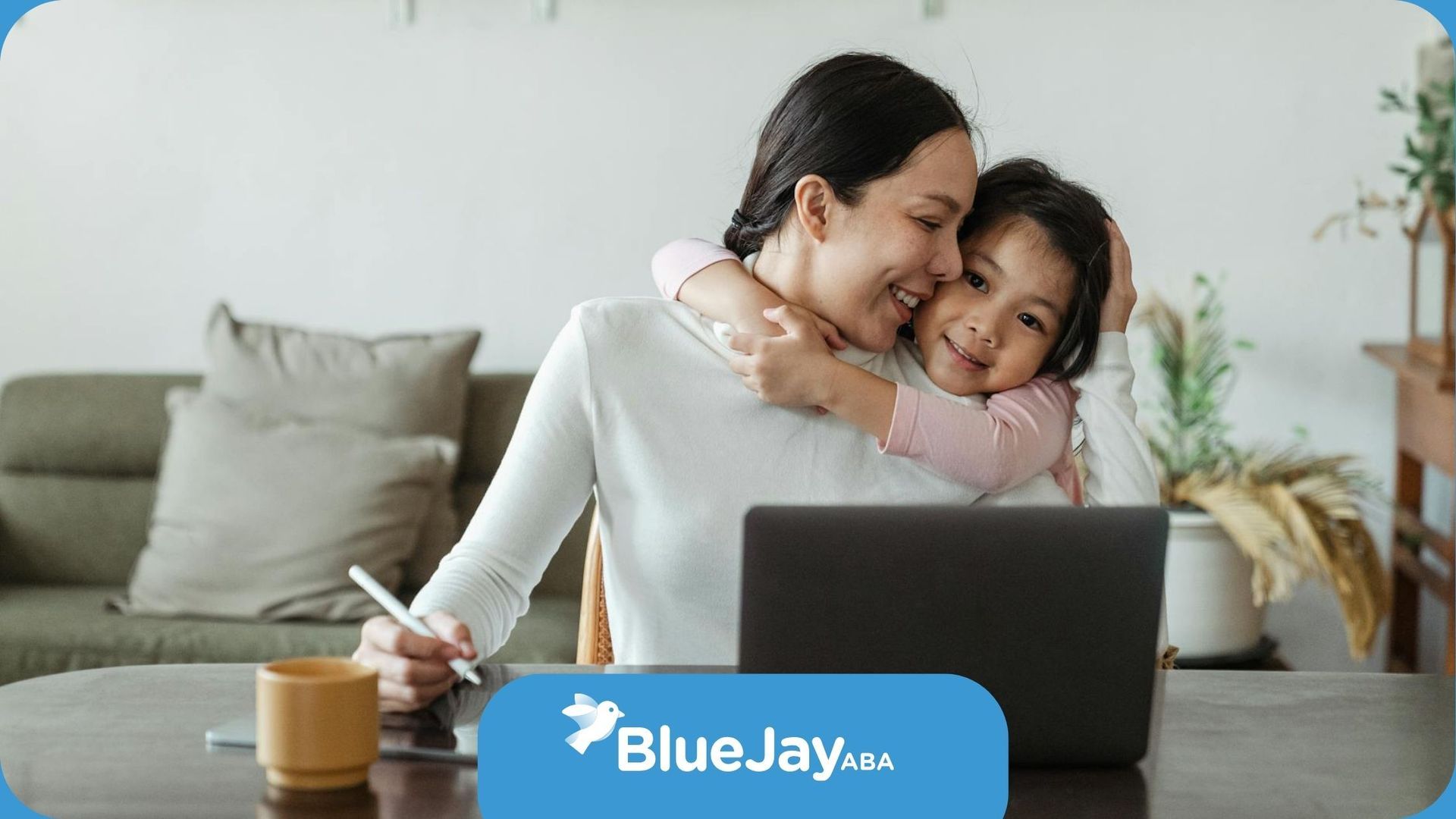 A smiling autistic child tightly hugging mom while she works on laptop at home in North Carolina.