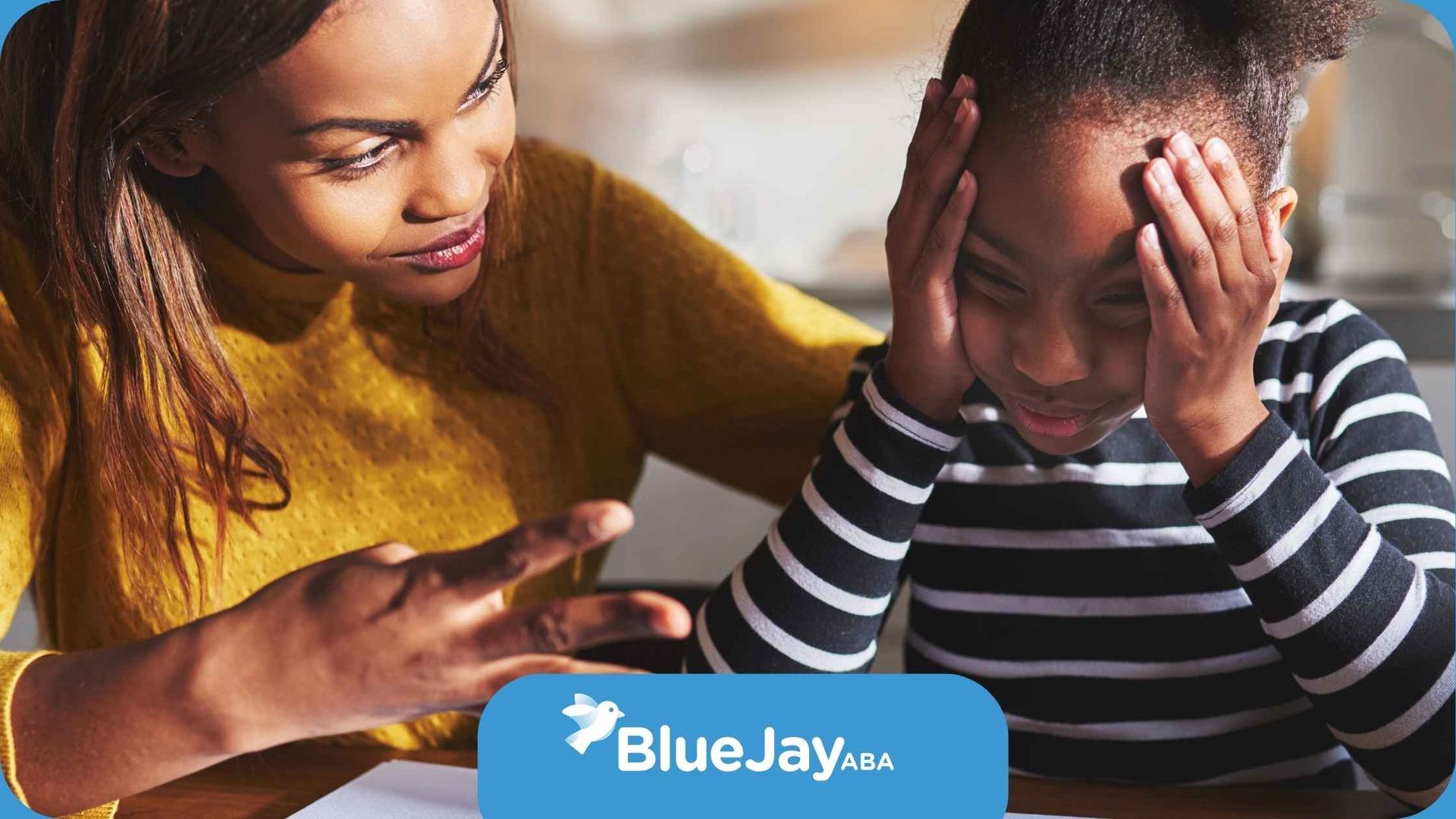 A woman is talking to a young girl who is sitting at a table with her hands on her head.