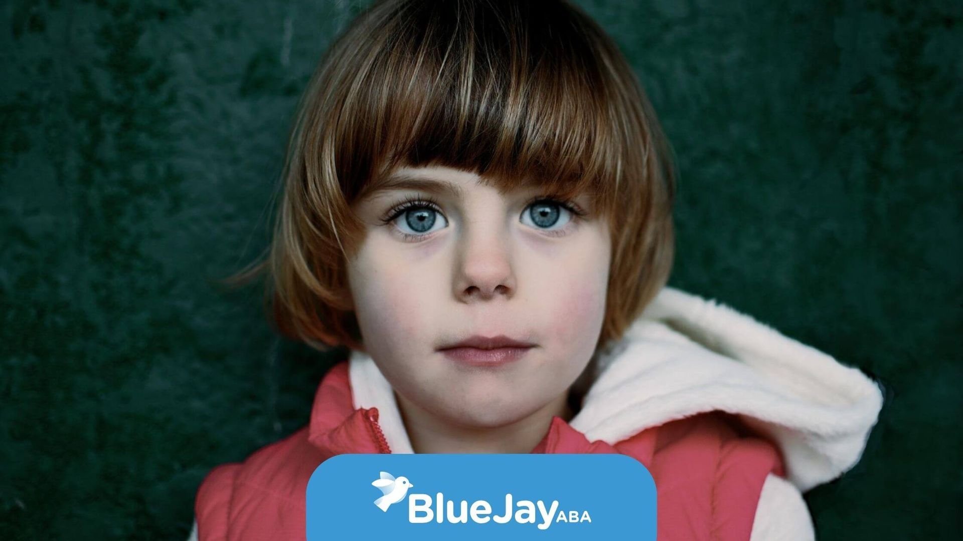 Close-up portrait of a young child with blue eyes and a brown bob haircut in ABA therapy.