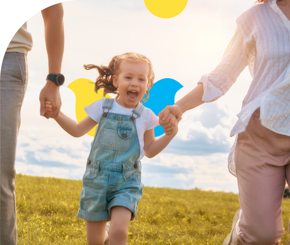 A family is holding hands and running in a field.