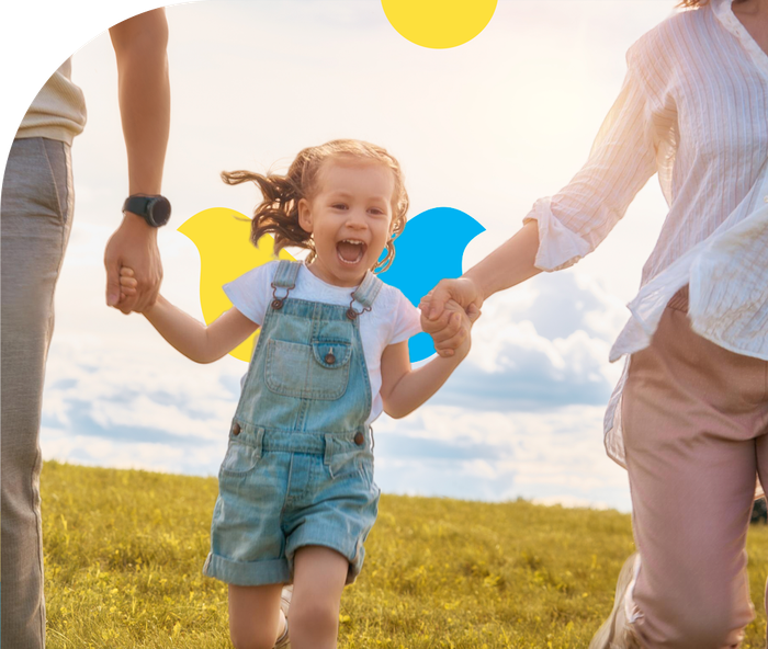 A family is holding hands and running in a field.