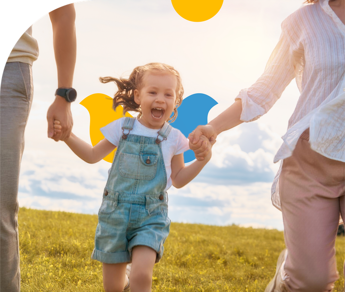 A family is holding hands and running in a field.