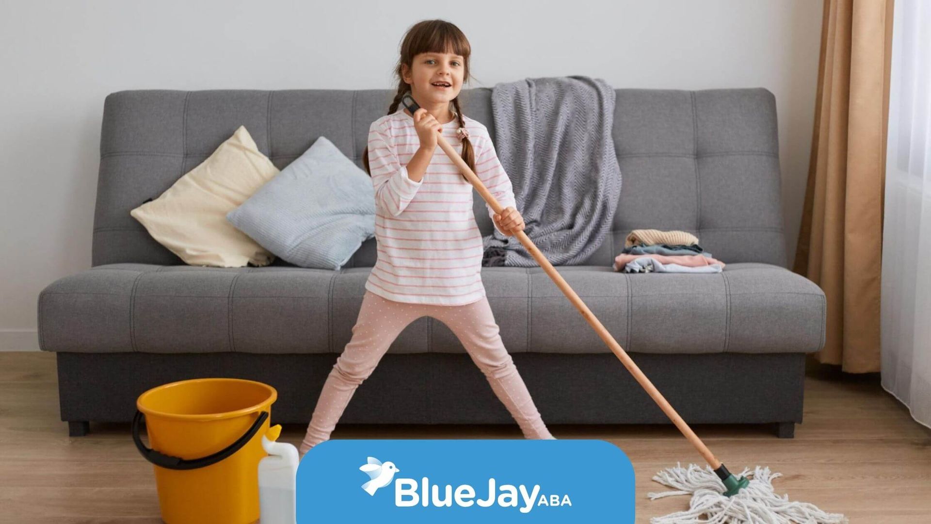 Smiling girl with autism mopping the floor with a bucket nearby in a cozy living room.