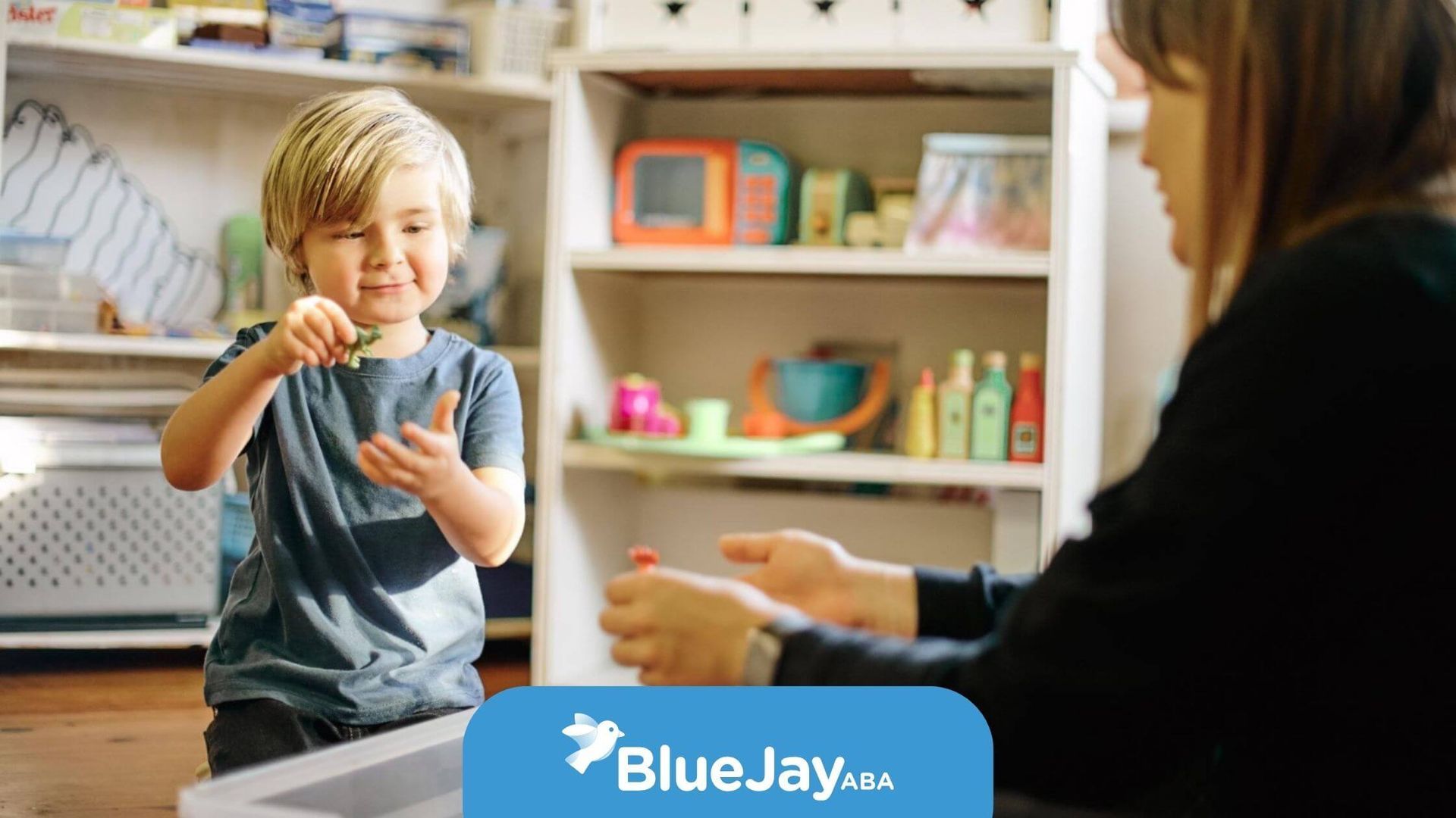 A young boy smiling while playing with toys in an ABA therapy session.