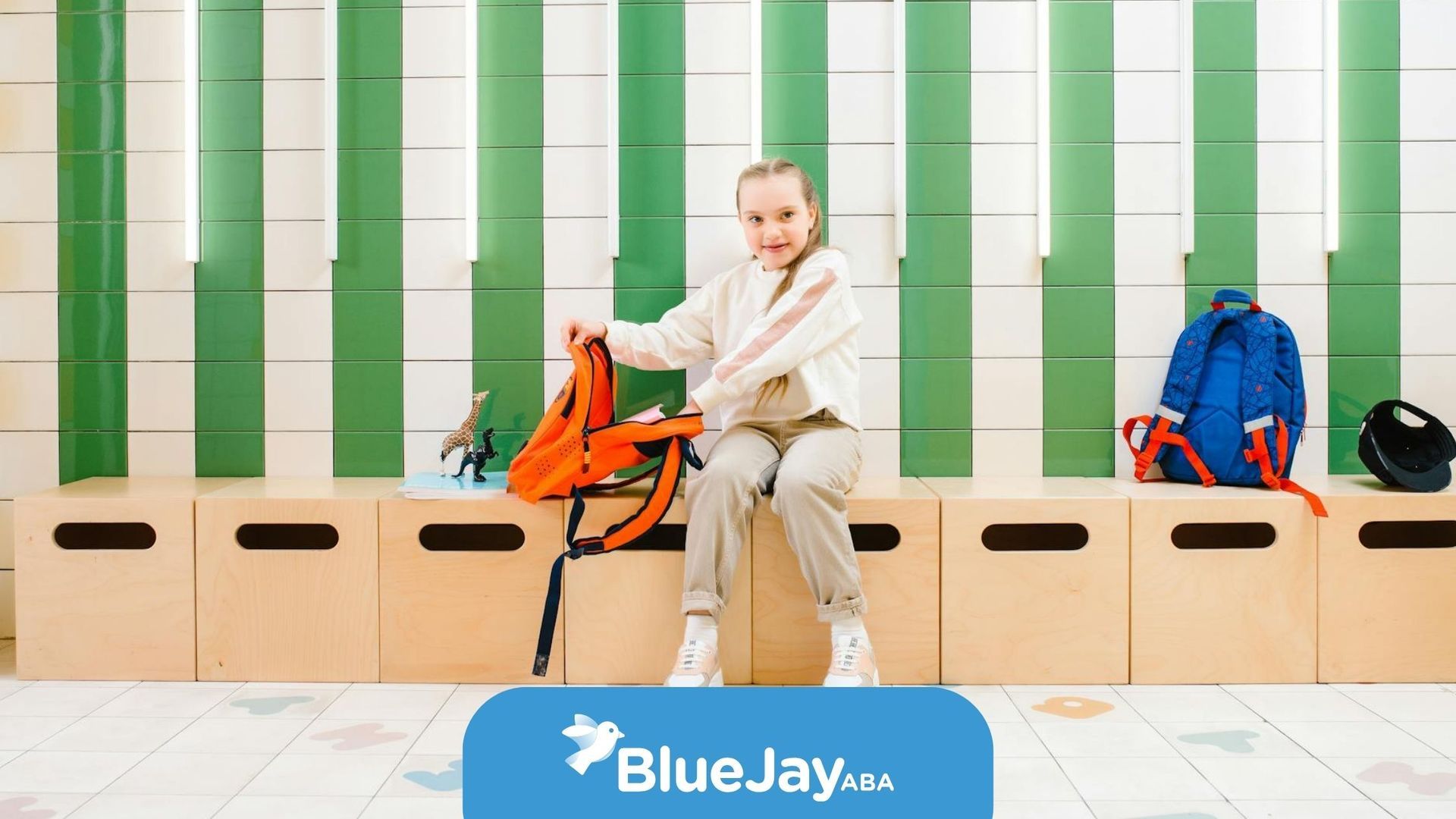 Autistic child sitting on bench with an orange backpack in a tiled hallway after ABA therapy in NC.