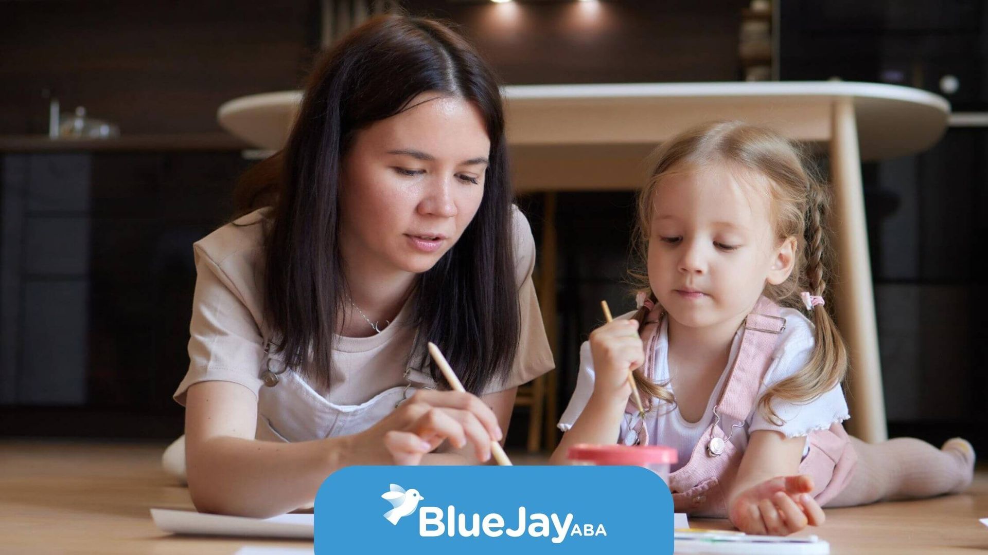 BCBA and autistic girl painting together in ABA therapy.