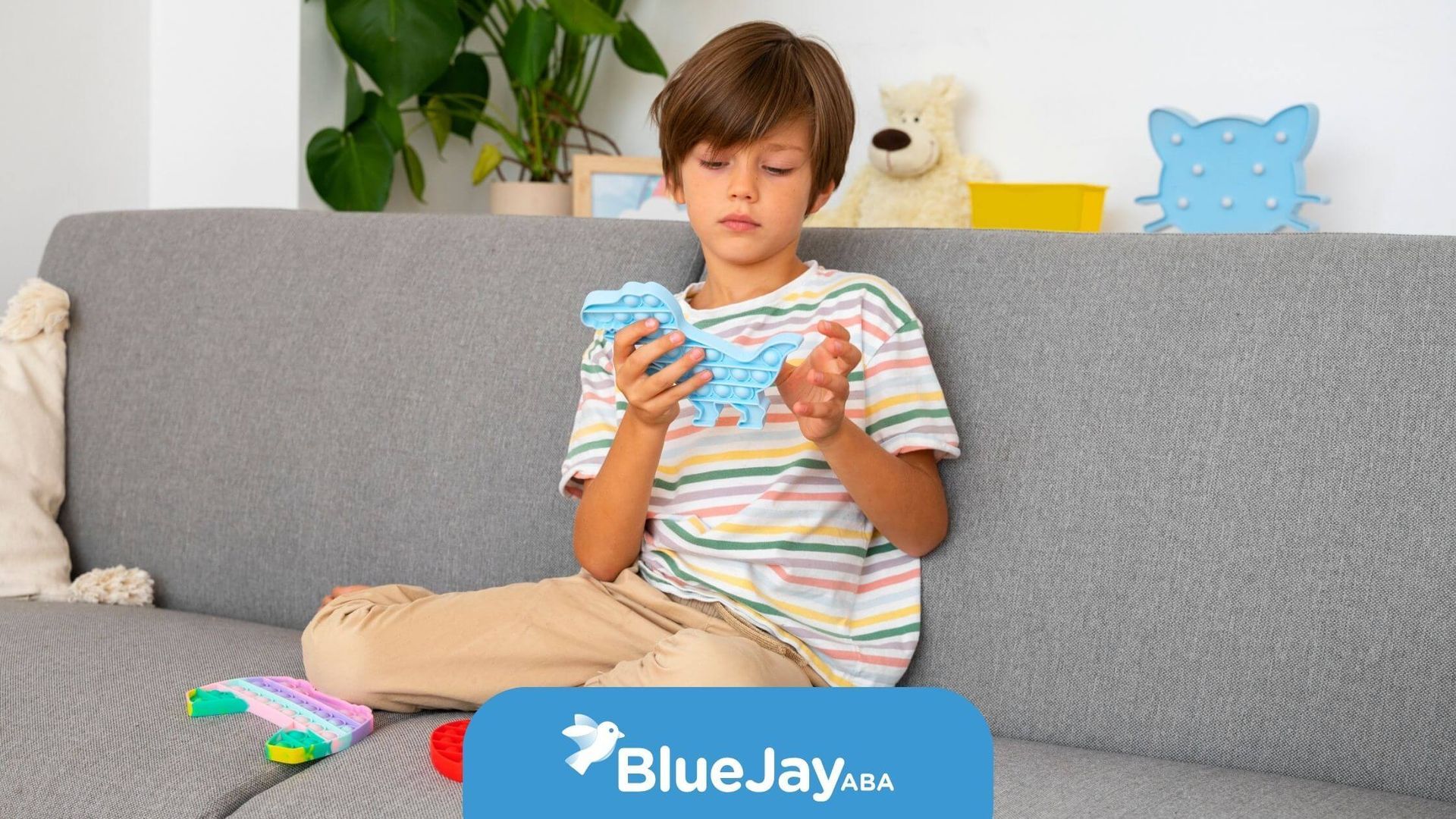 A child sitting on a sofa playing with colorful pop it toys after ABA therapy in North Carolina.