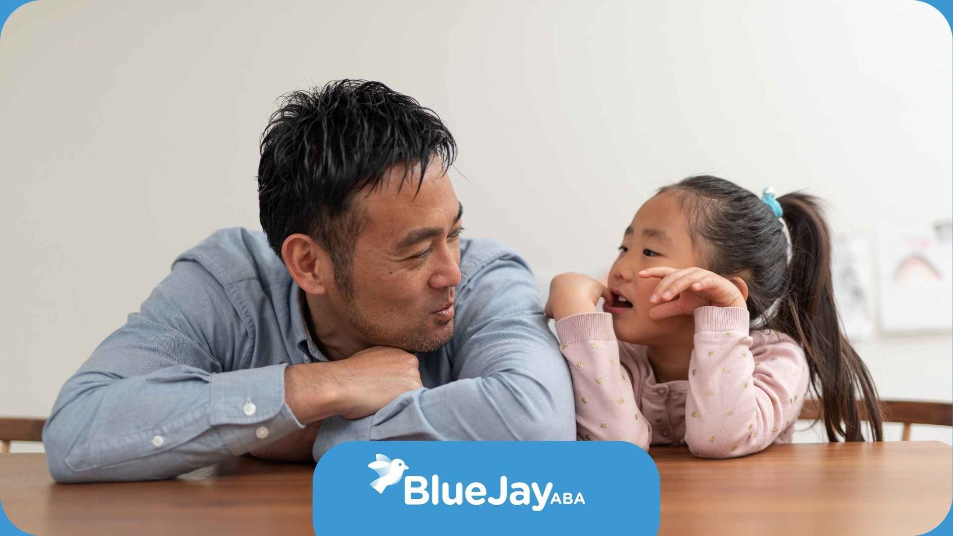 A man and a little girl are sitting at a table talking to each other.