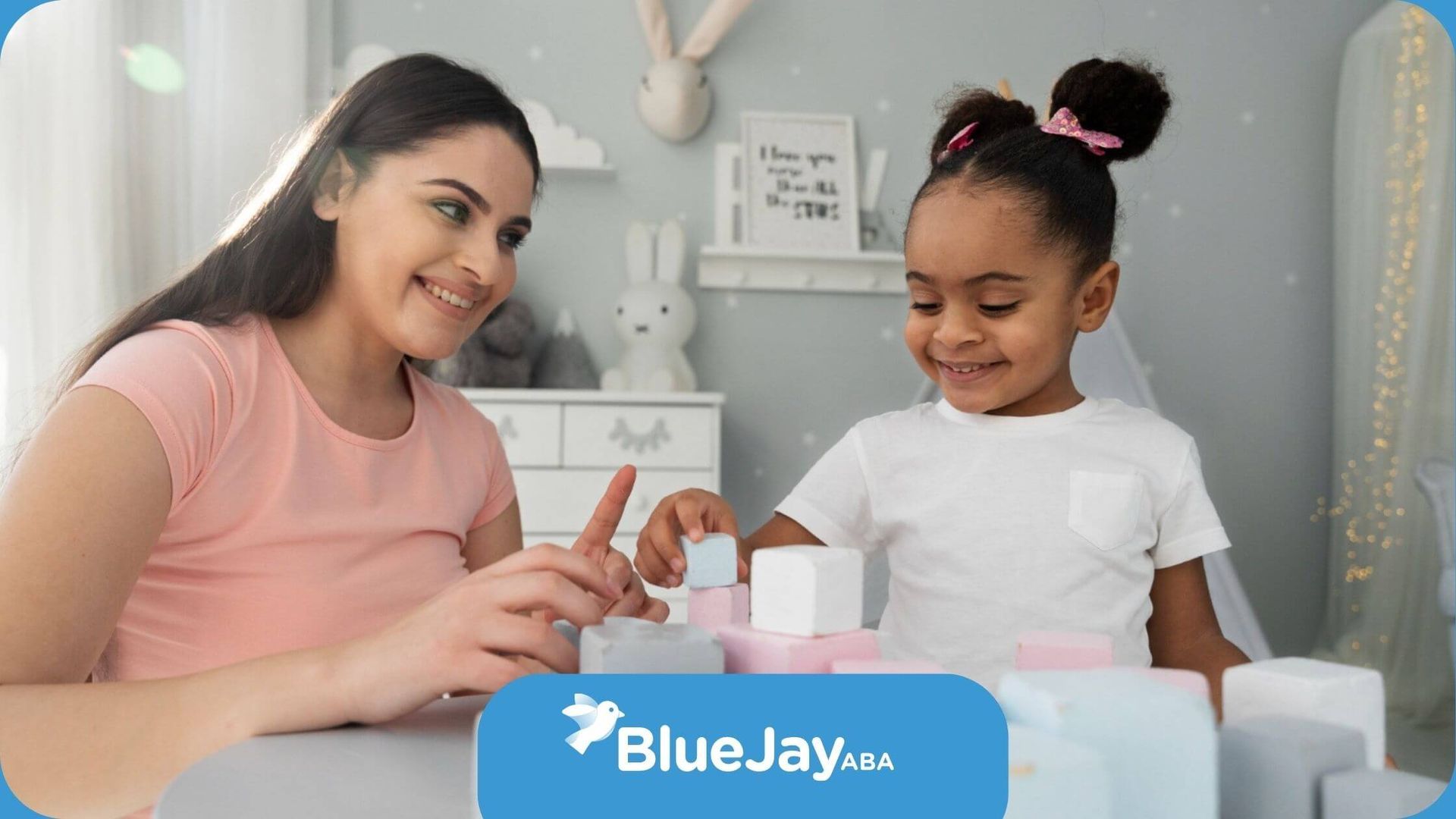 A BCBA and a little girl are playing with blocks at a table in ABA therapy.