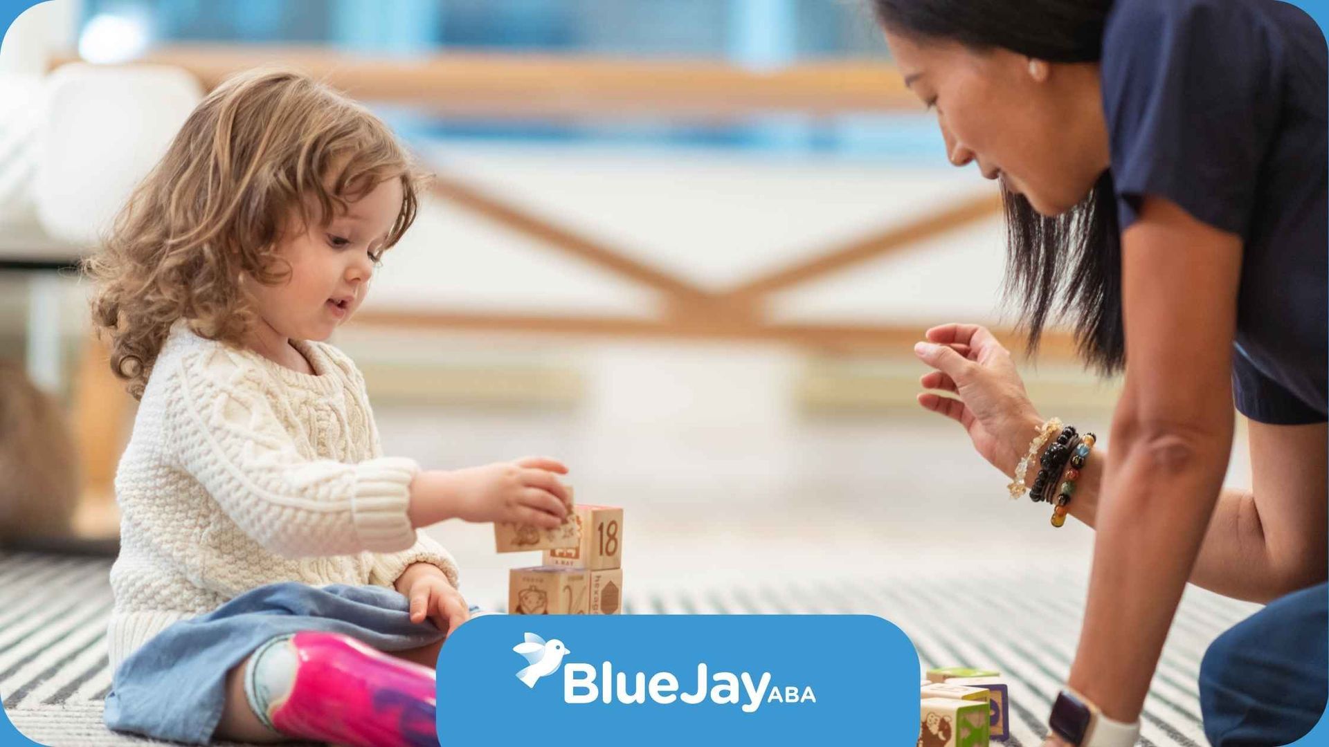 A woman and a little girl are playing with wooden blocks on the floor.