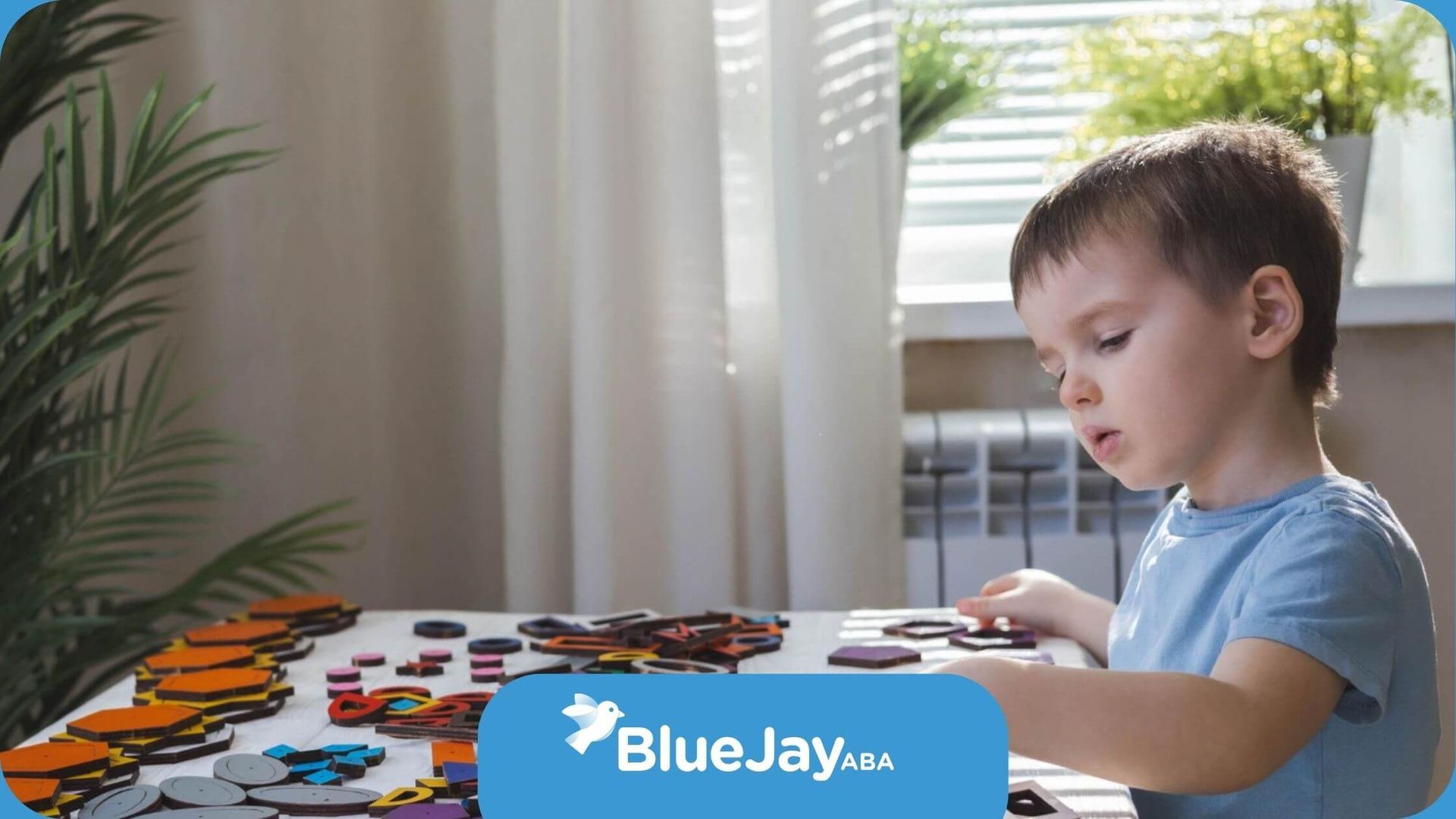 A young boy is sitting at a table playing with puzzles in ABA therapy.