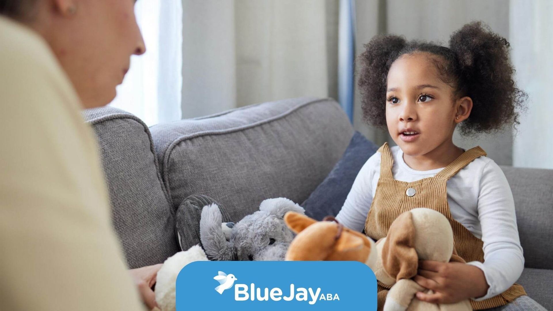 A little girl engaging in imaginative play with stuffed animals with a BCBA.