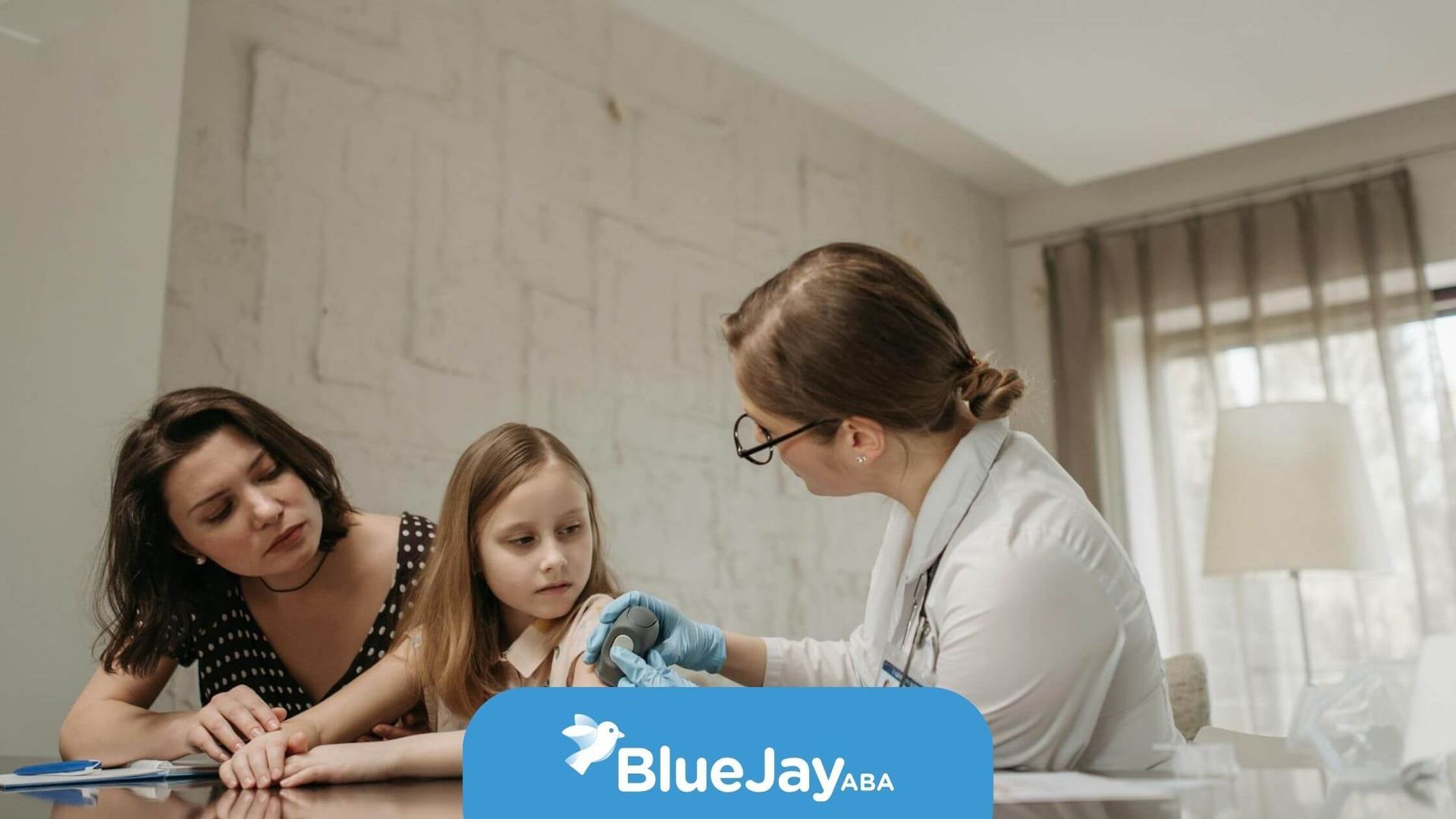 ABA therapist giving a young autistic girl a vaccine shot while her mother watches closely.
