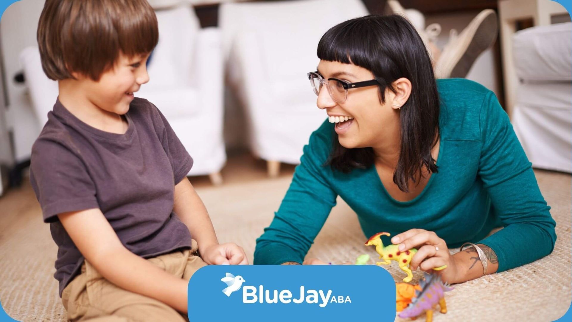 A BCBA and a child are playing with toy dinosaurs on the floor in ABA therapy.