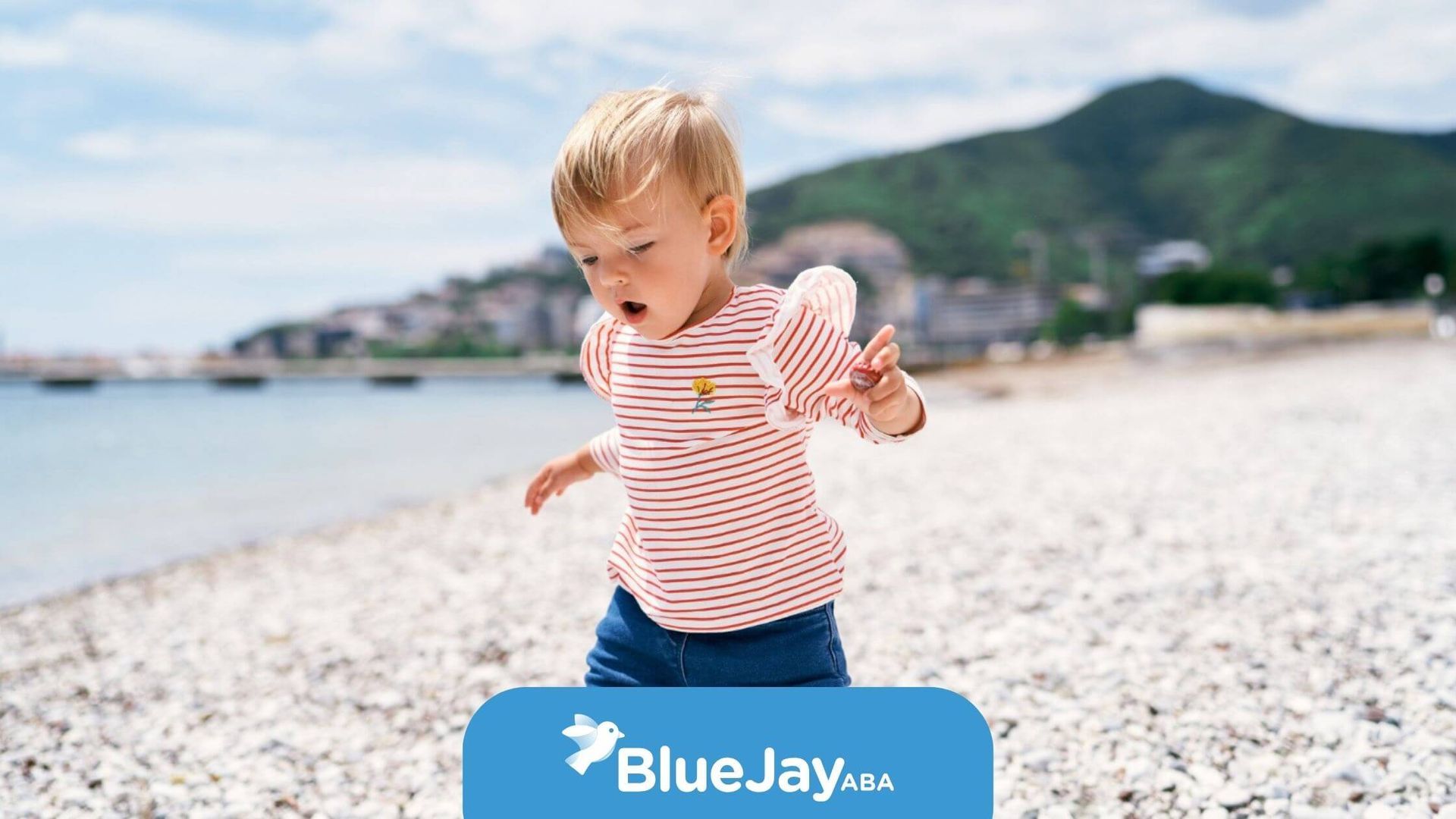 Toddler with autism walking along a rocky beach shoreline.