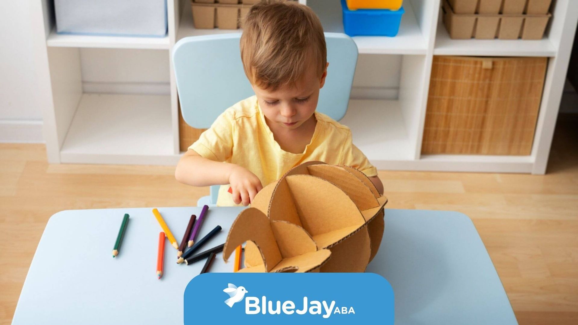 A child playing with a cardboard structure and colored pencils during ABA therapy.