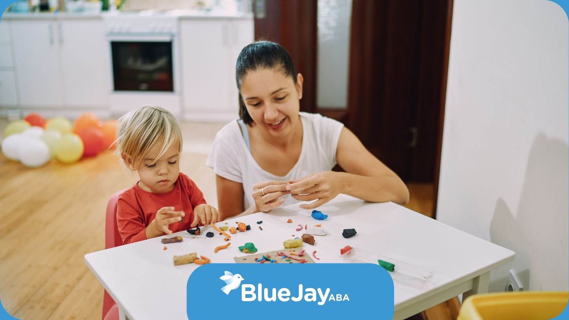 An ABA therapist and a child are sitting at a table playing with clay in ABA therapy.