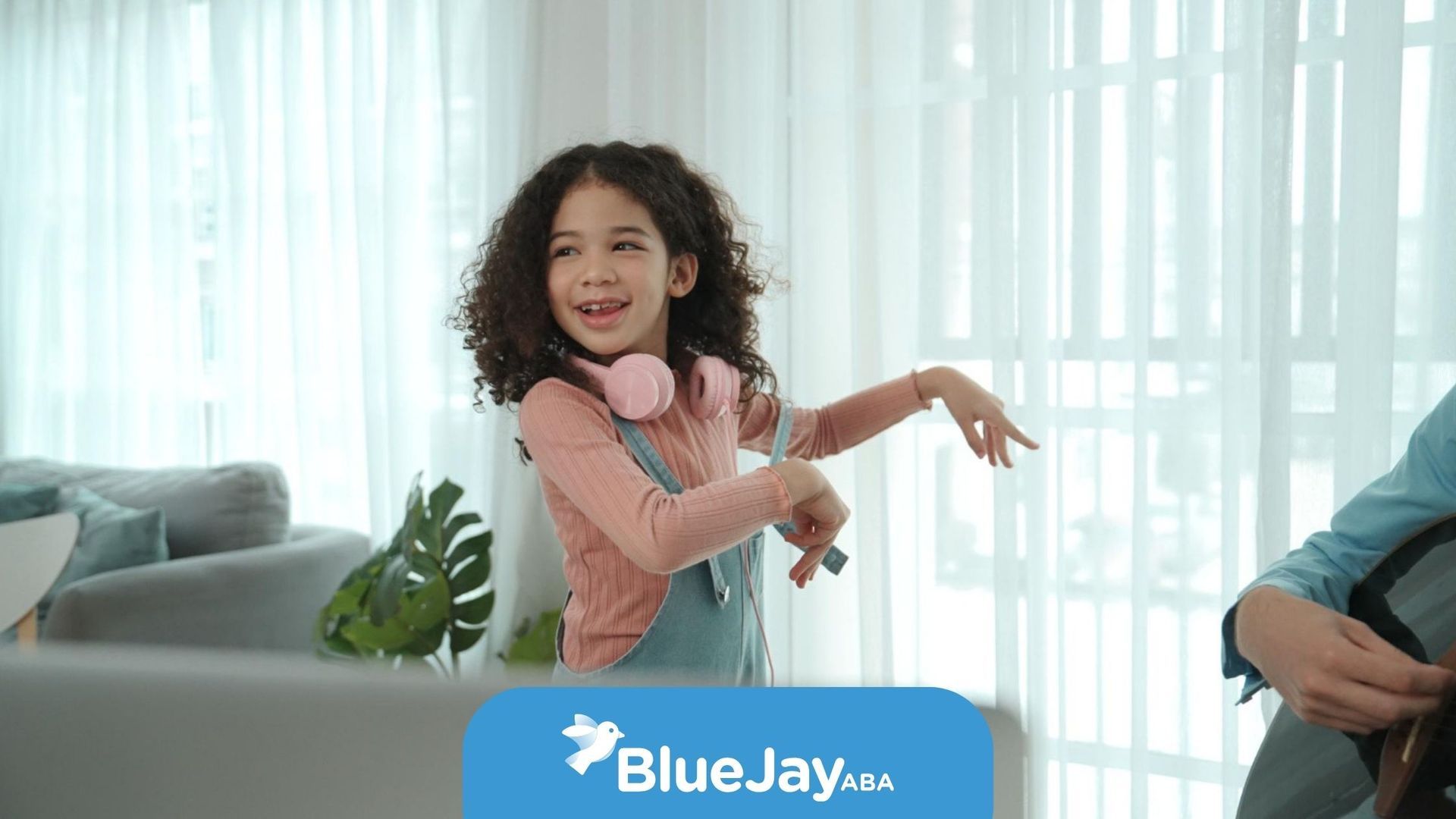 Smiling child with headphones dancing indoors.