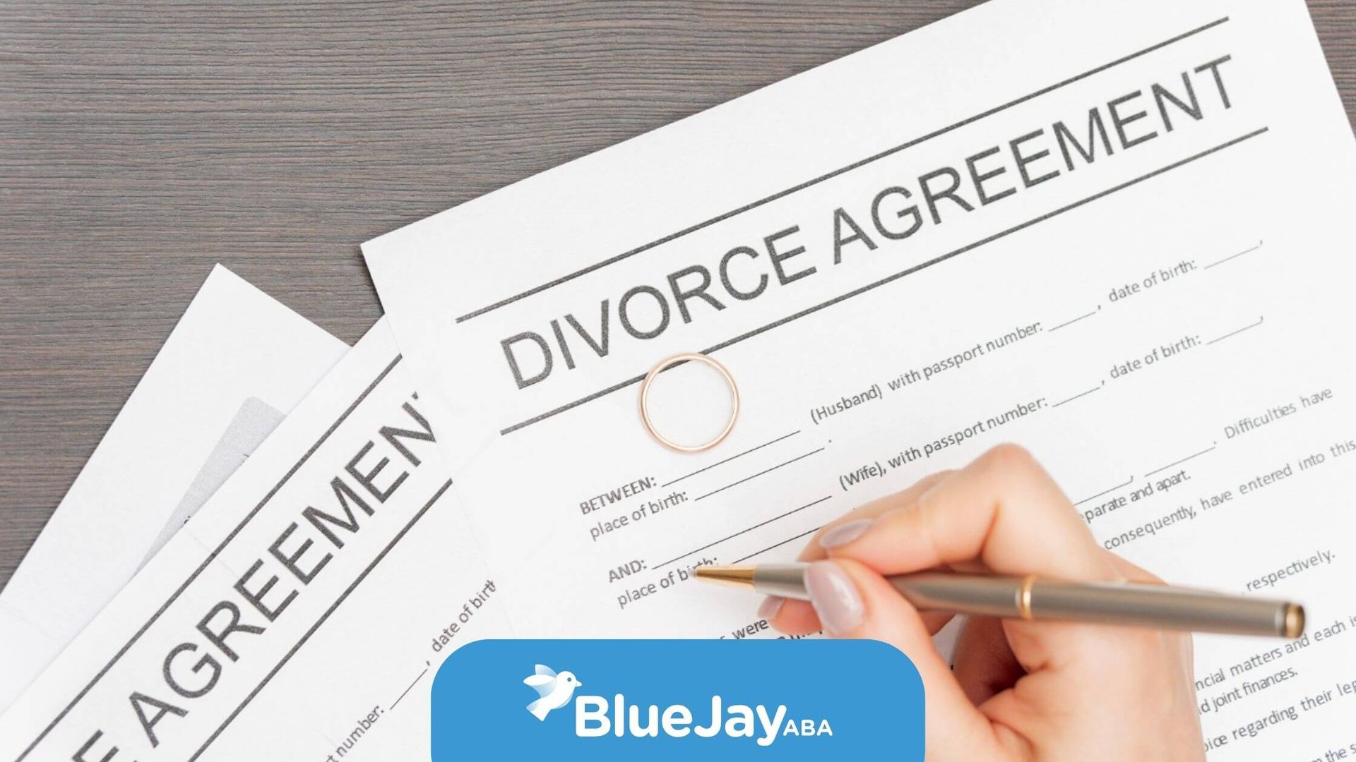 Person signing divorce papers with a ring on the document.