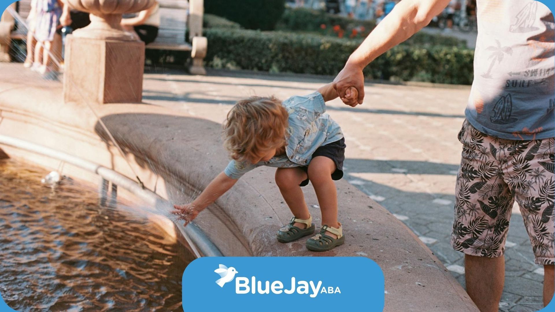 An autistic child reaching into a water fountain while being held by an ABA therapist in NC.