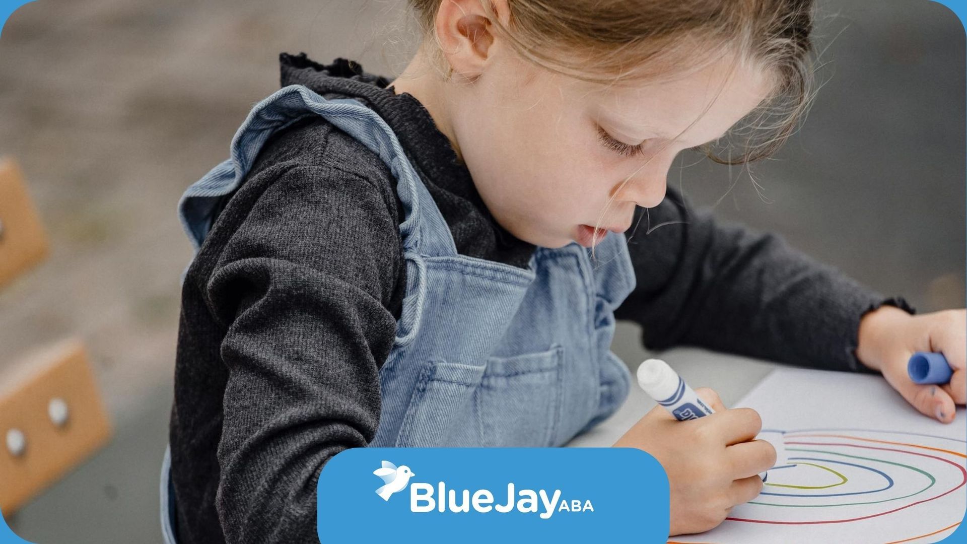 An autistic girl coloring a rainbow with crayons during ABA therapy session in North Carolina.
