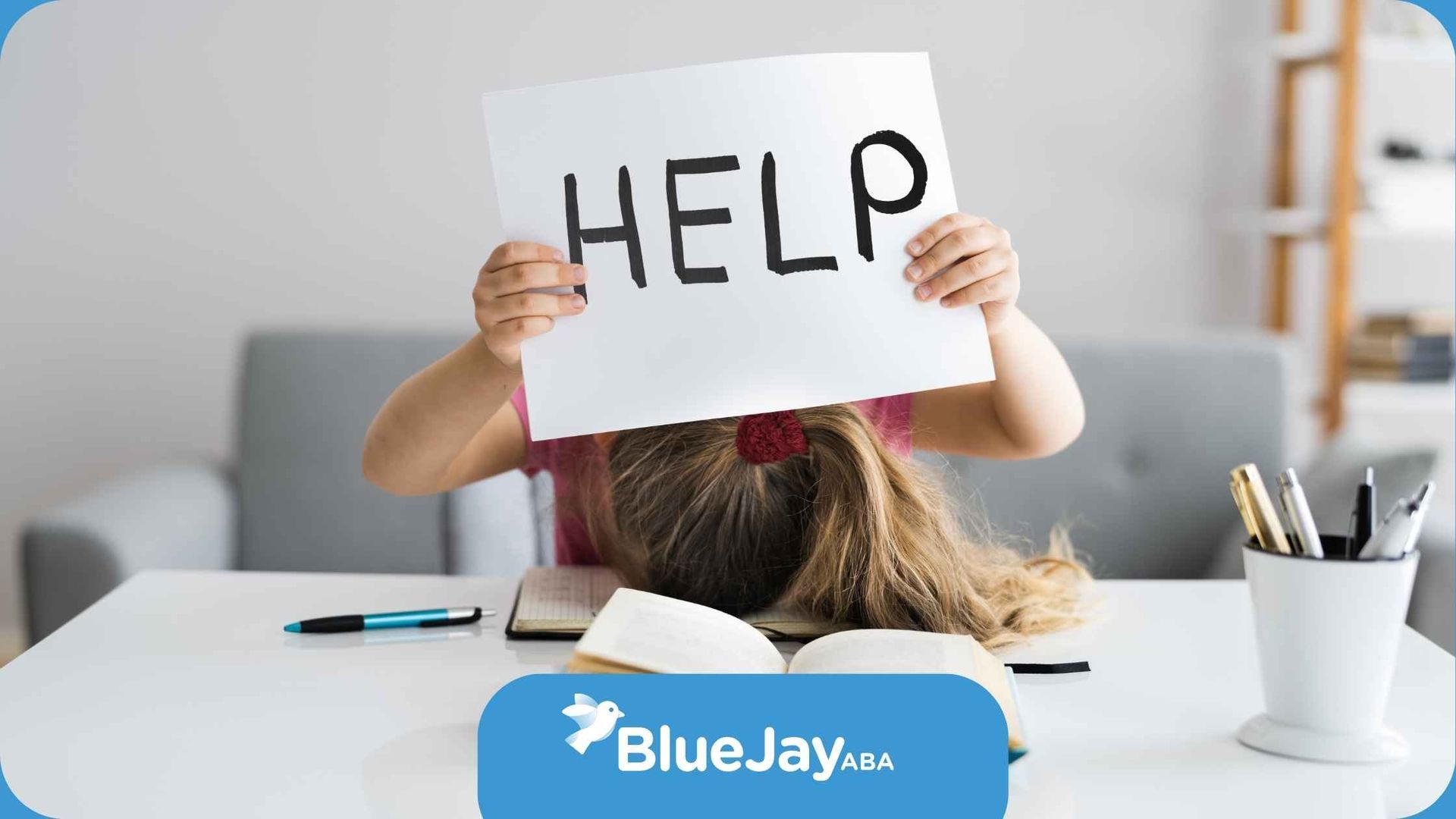 A little girl is sitting at a desk holding a sign that says 