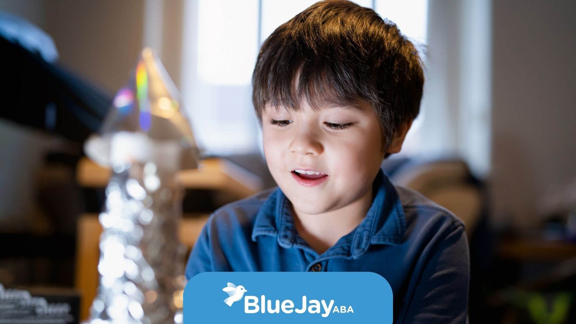Autistic boy smiling while working on a DIY craft model made of foil and cardboard after therapy.