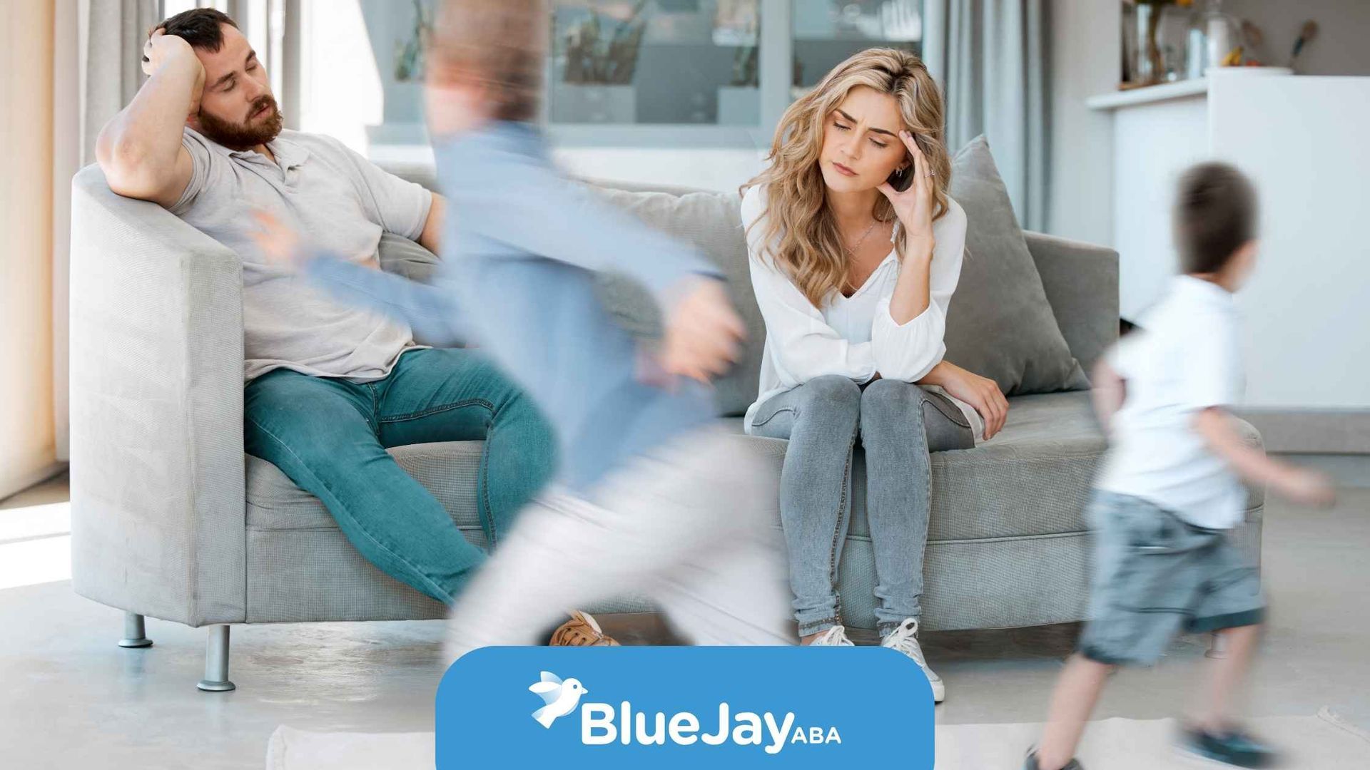 Parents on couch overwhelmed by running child.
