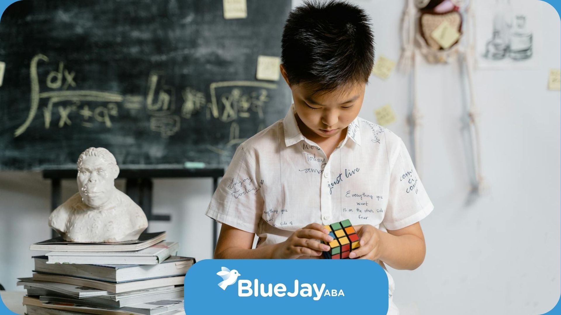 Autistic boy playing with Rubik’s cube in front of a chalkboard during in-school ABA therapy in NC.