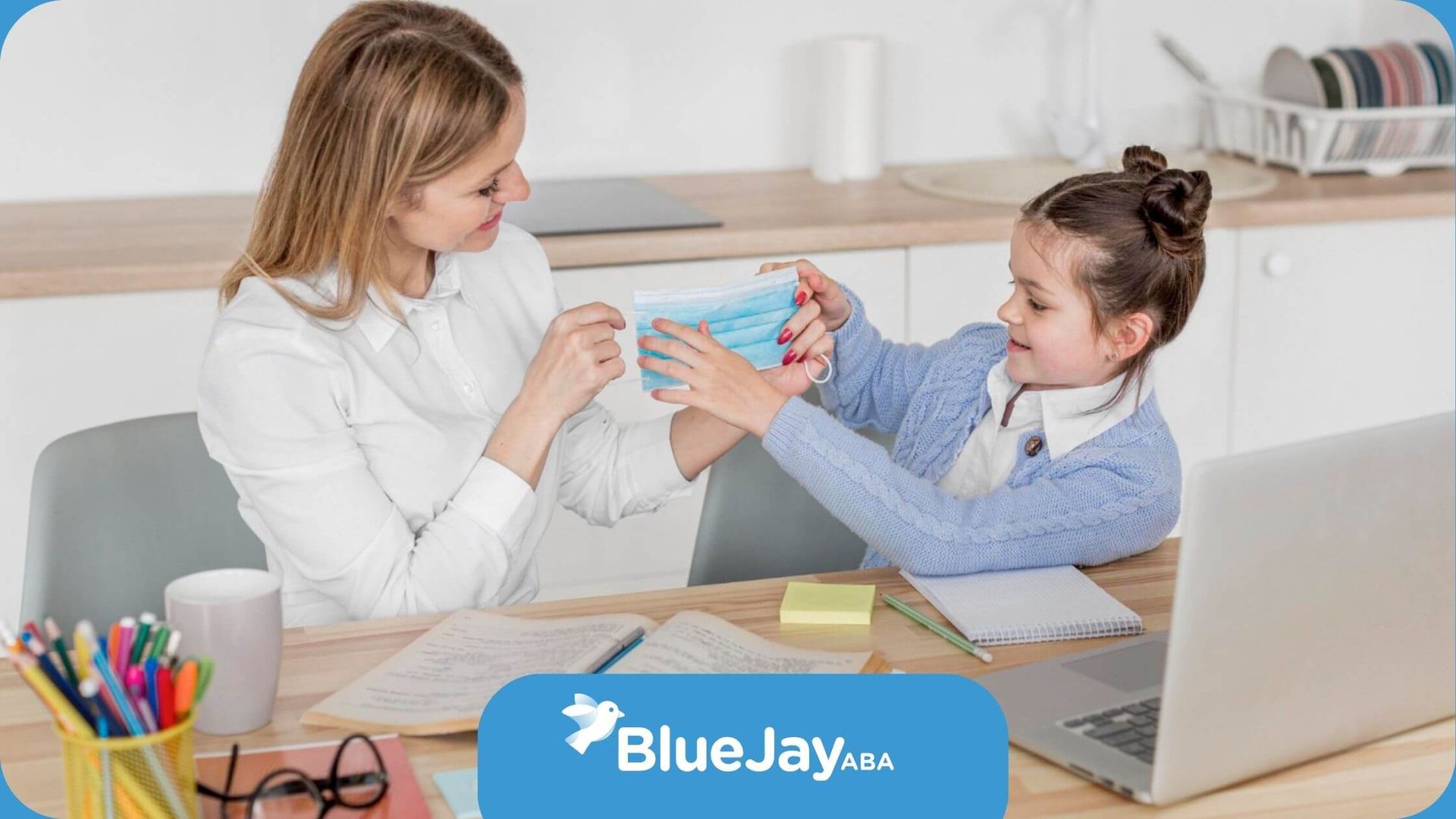 A BCBA and a little girl are sitting at a table with a laptop in ABA therapy.