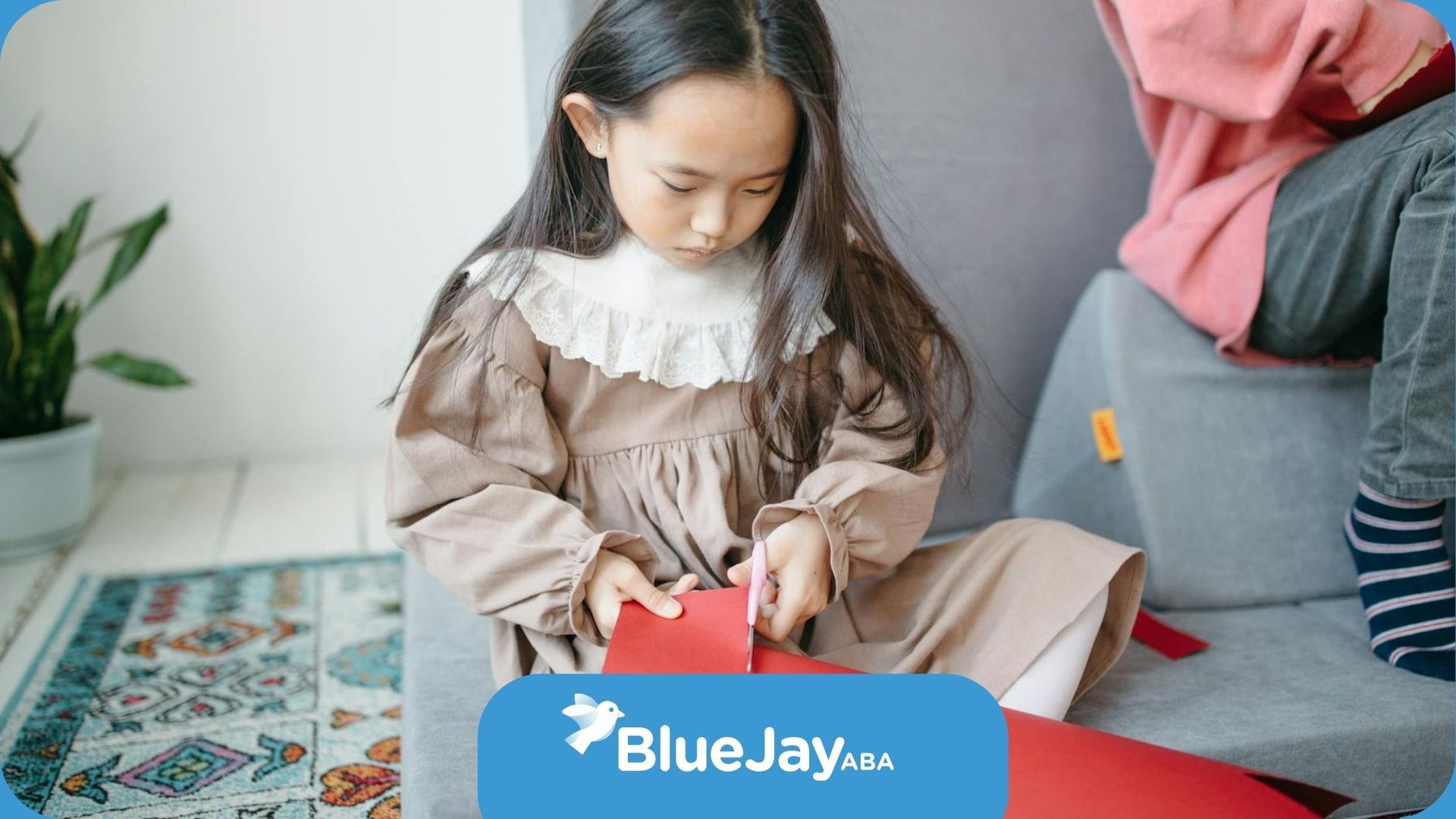 Autistic child cutting a red piece of paper during an arts & crafts ABA therapy session in Colorado.