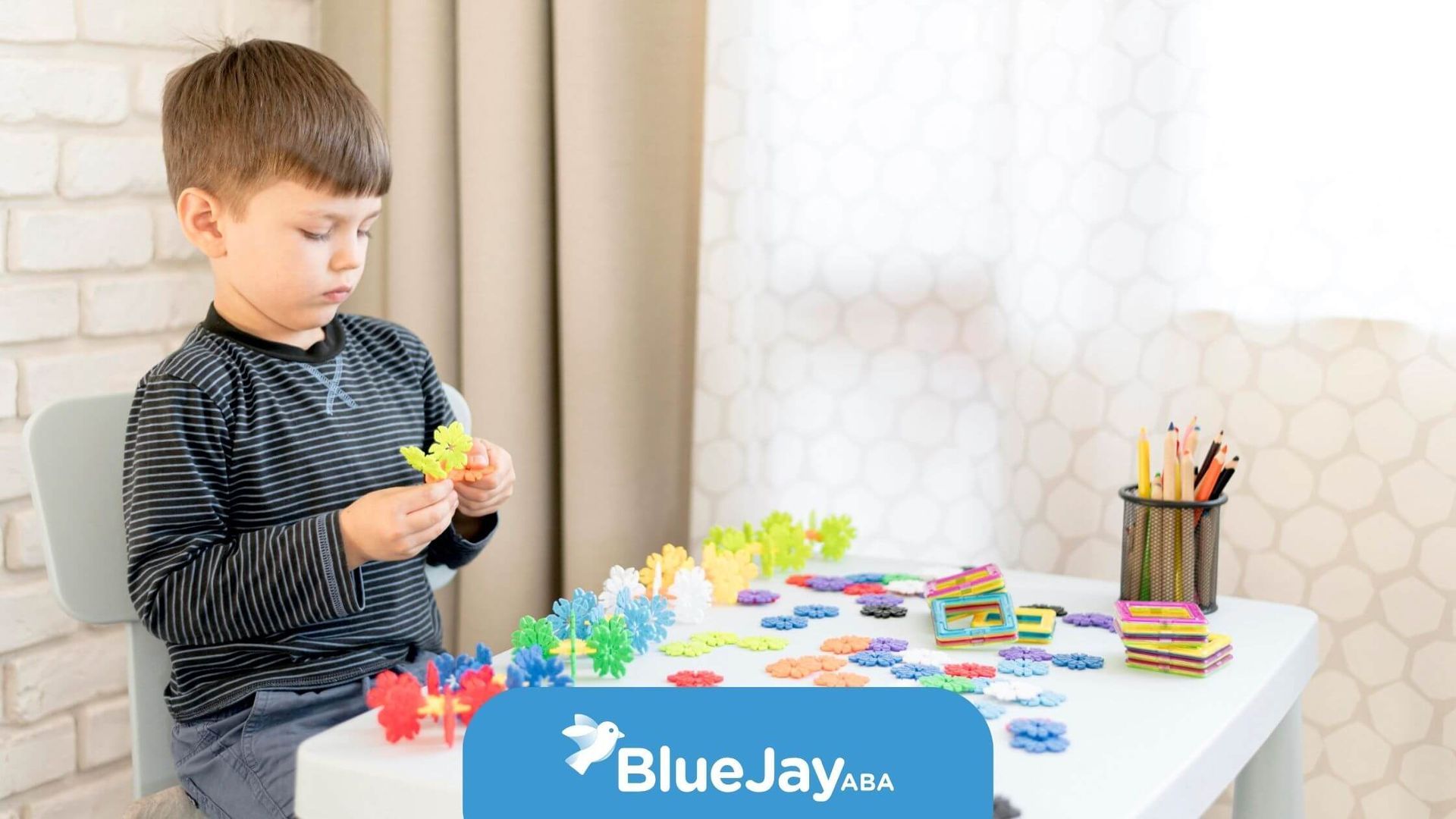 Autistic child concentrating while assembling colorful toy pieces at a table after ABA therapy.