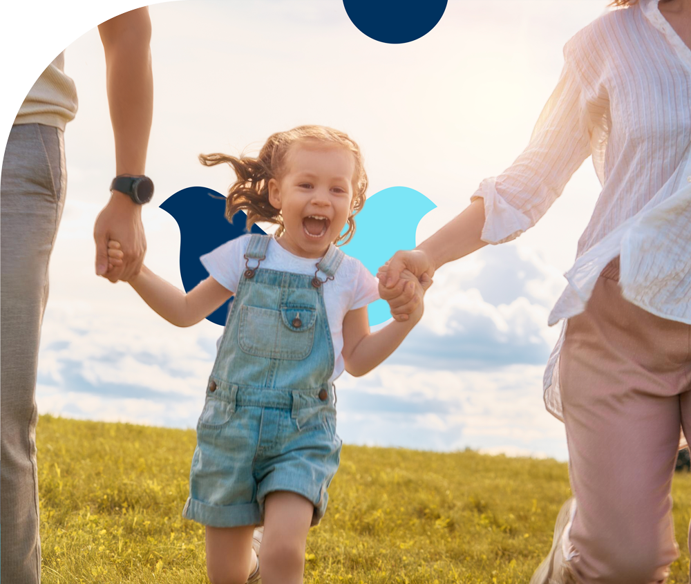 A family is holding hands and running in a field.