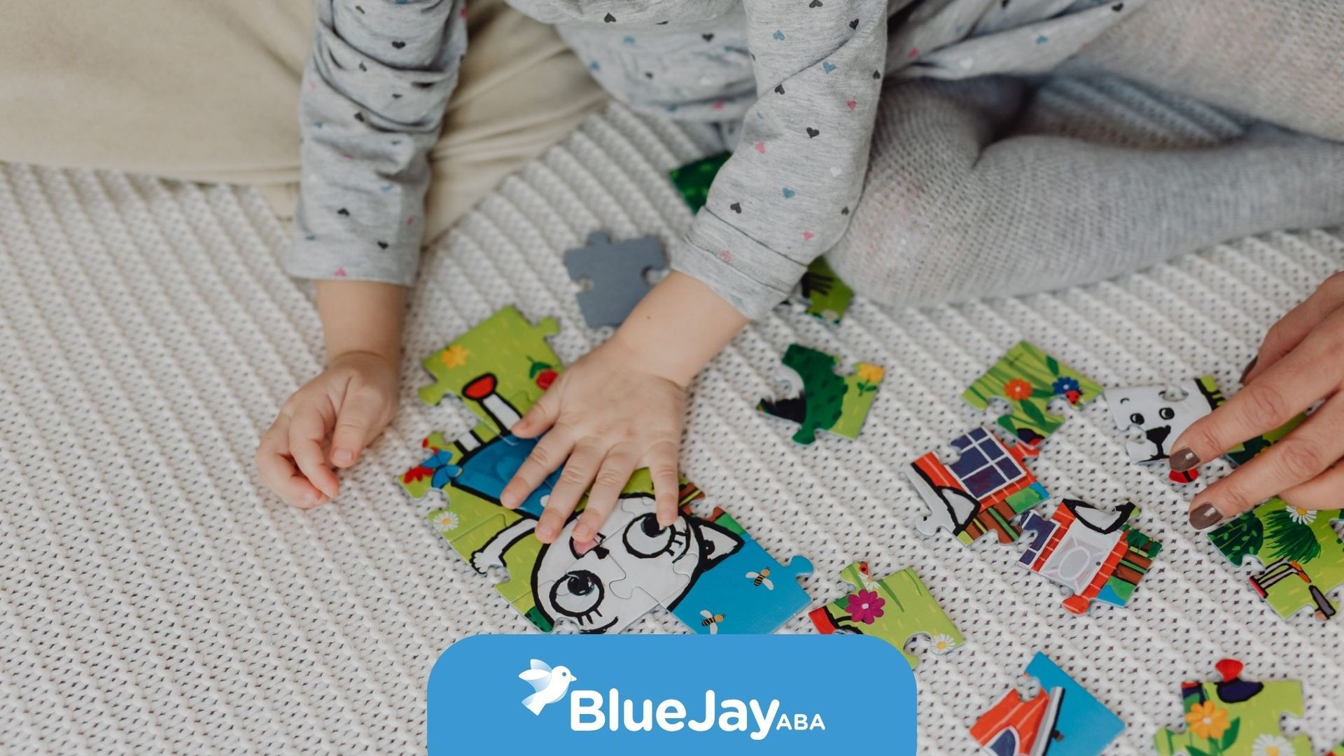 Child and adult working together on a colorful puzzle on a white blanket. BlueJay logo in the corner.