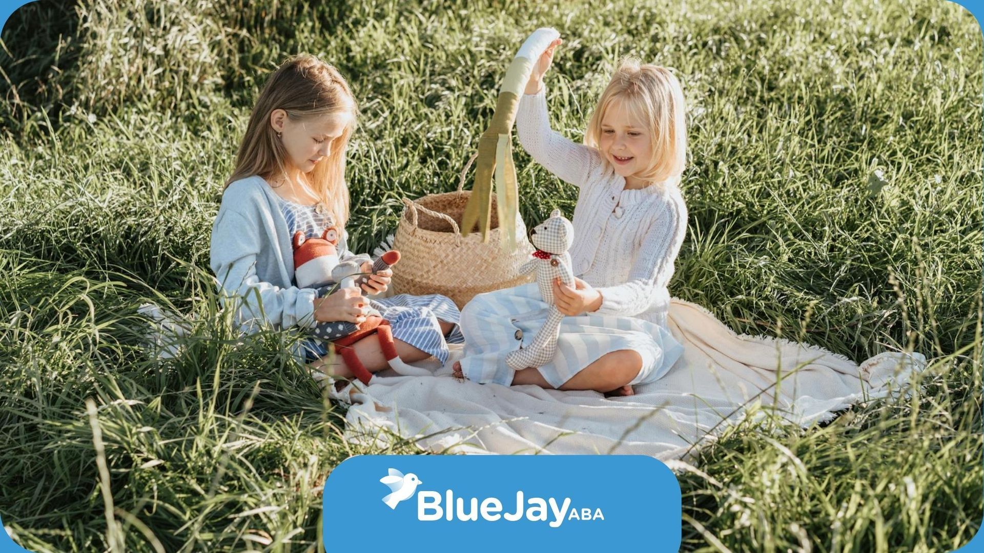 Two autistic girls playing with stuffed toys during a picnic on a grassy field in North Carolina.