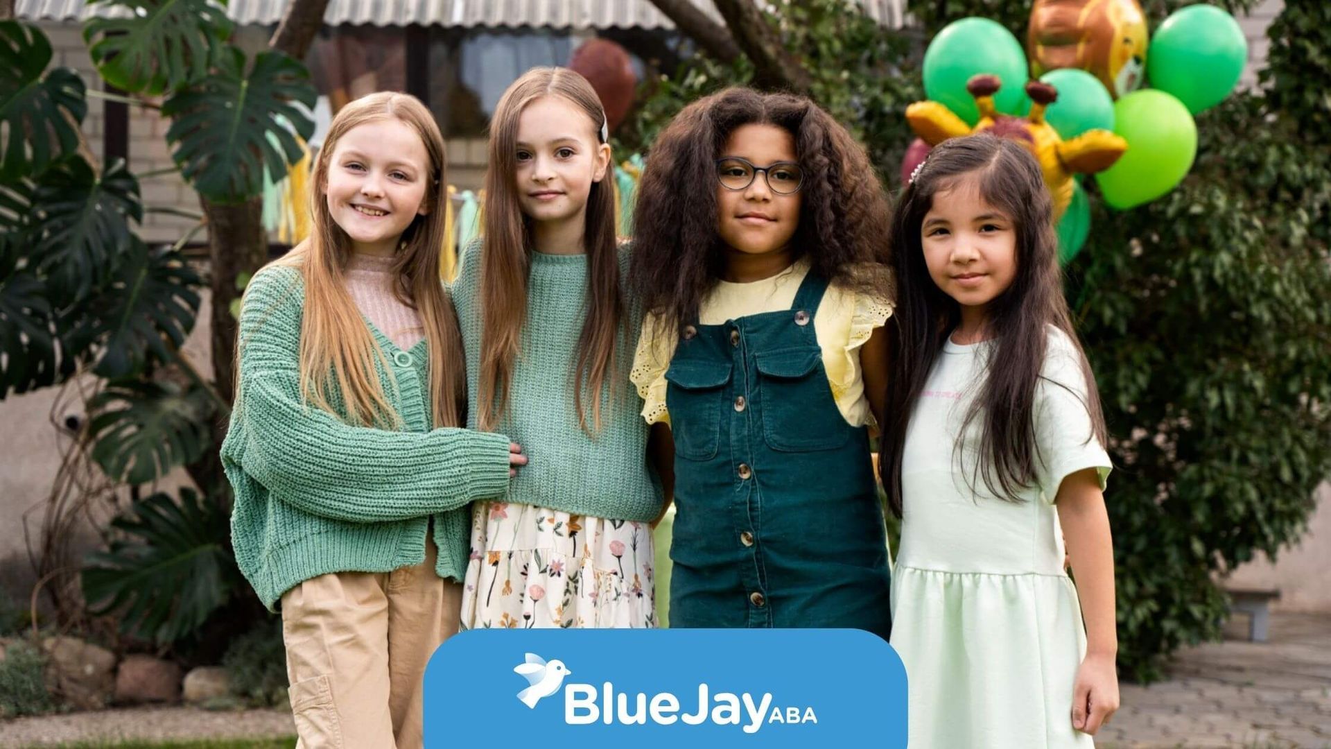 Four young girls with autism standing together at an outdoor party with balloons.