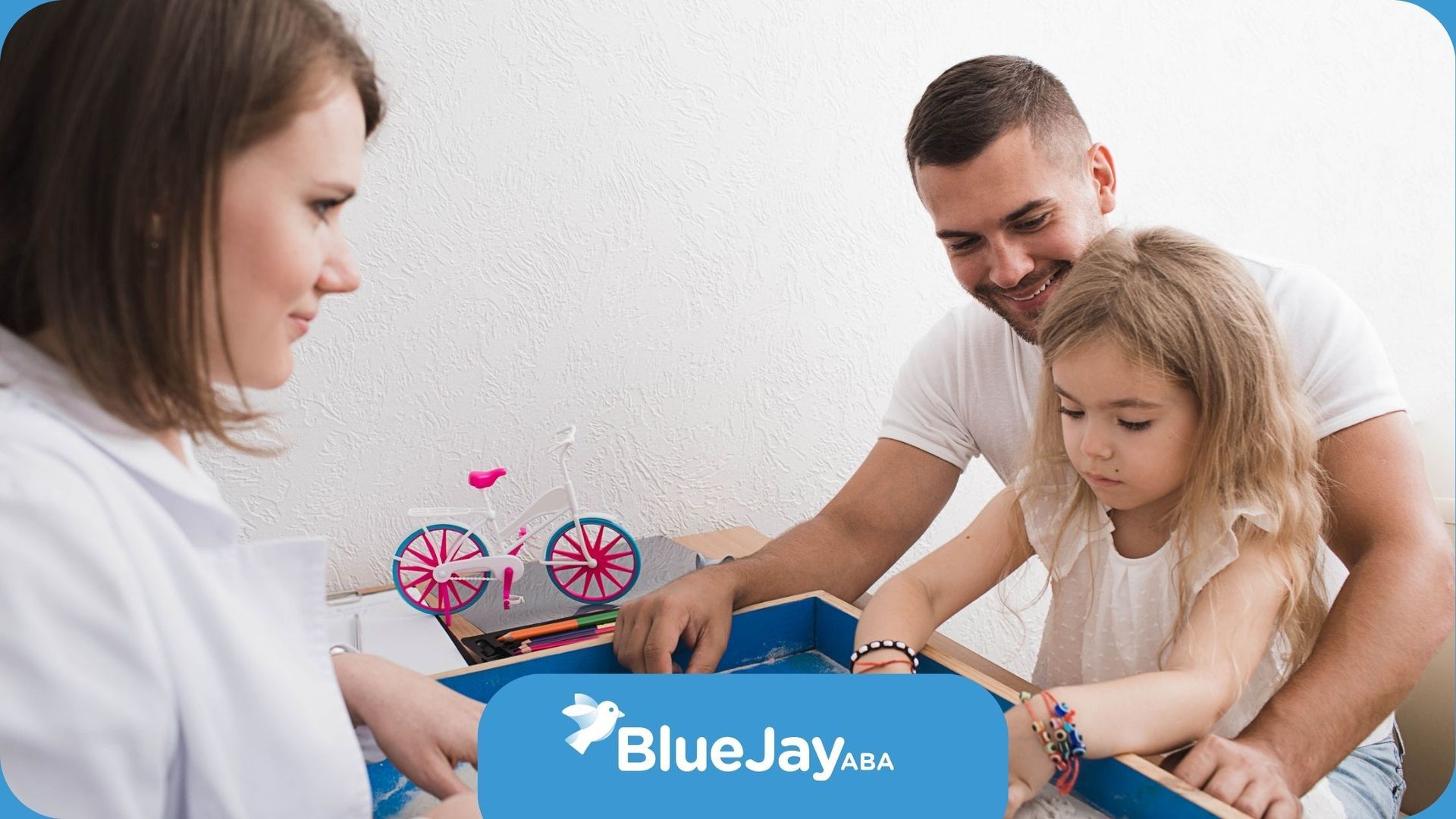 A man and a woman are playing with a little girl in a sandbox.