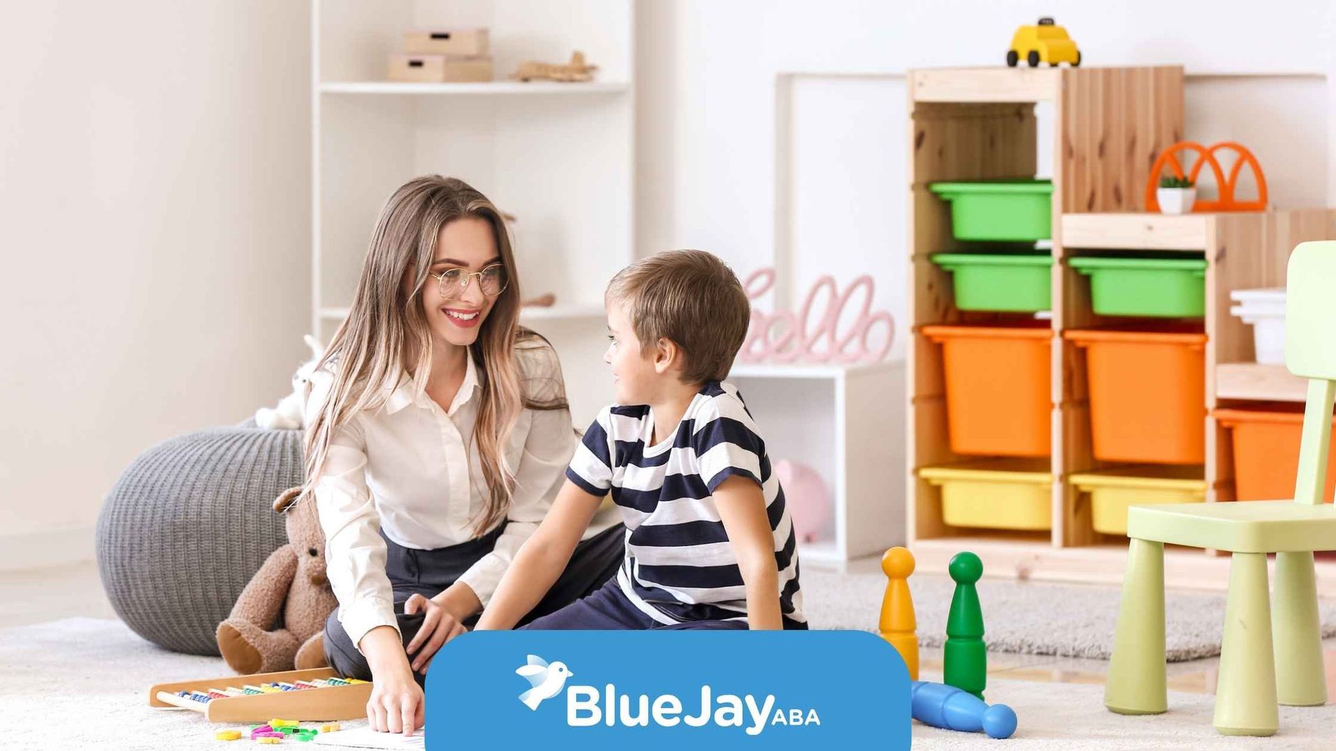 Woman and child playing in a brightly lit playroom with colorful toys. 